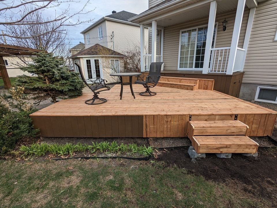 Une terrasse en bois avec une table et des chaises devant une maison.