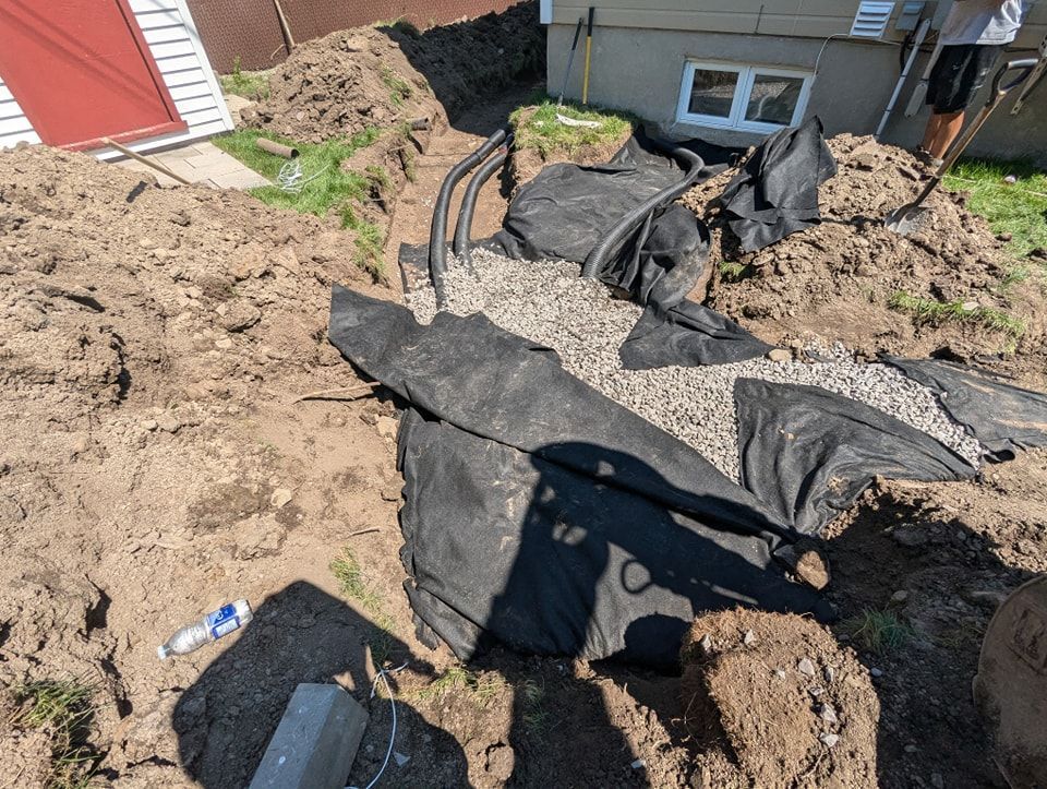 Une personne creuse un trou dans la terre devant une maison.