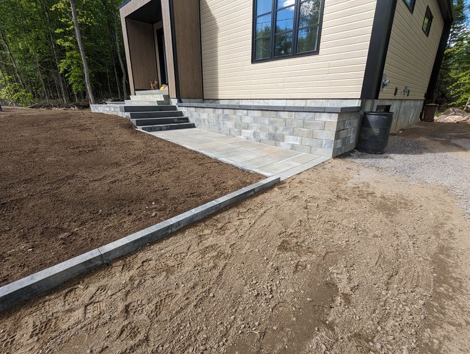 Une maison avec des escaliers qui y mènent est située au sommet d'un champ de terre.