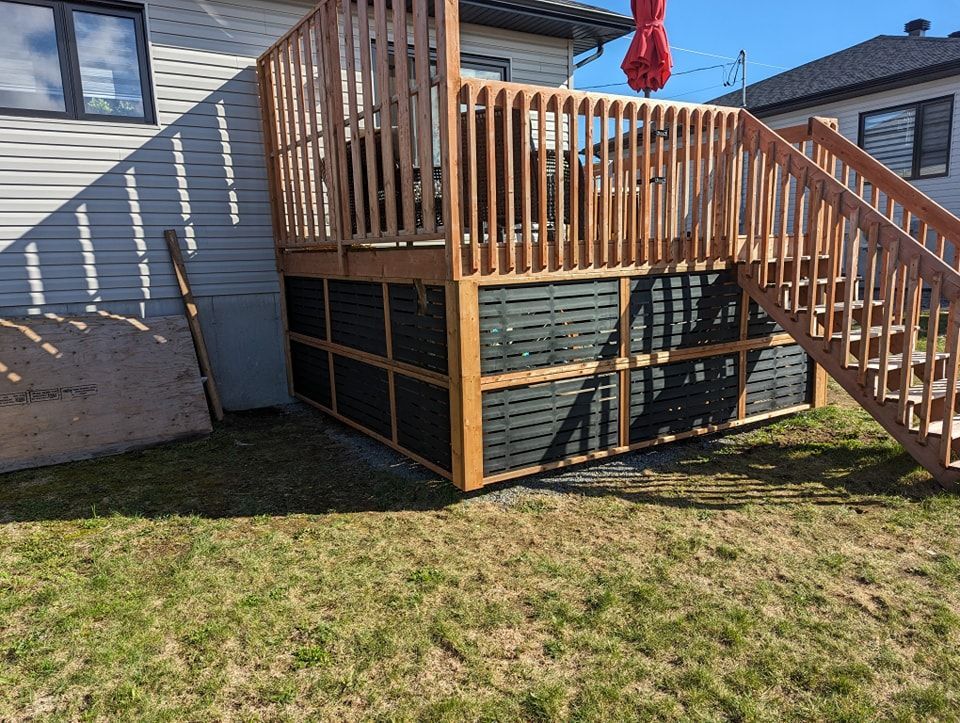 Une terrasse en bois avec des escaliers qui y mènent se trouve dans l'arrière-cour d'une maison.