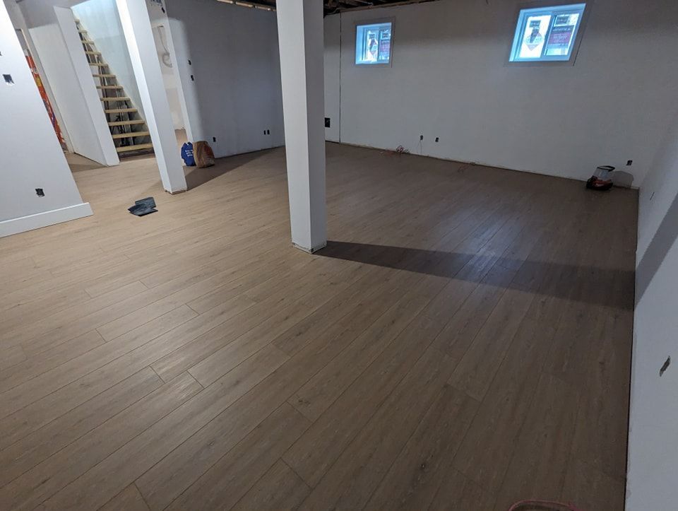 Une pièce avec un parquet et des murs blancs