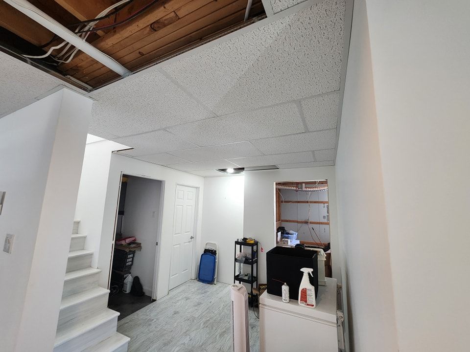 Un sous-sol avec un plafond blanc et des escaliers