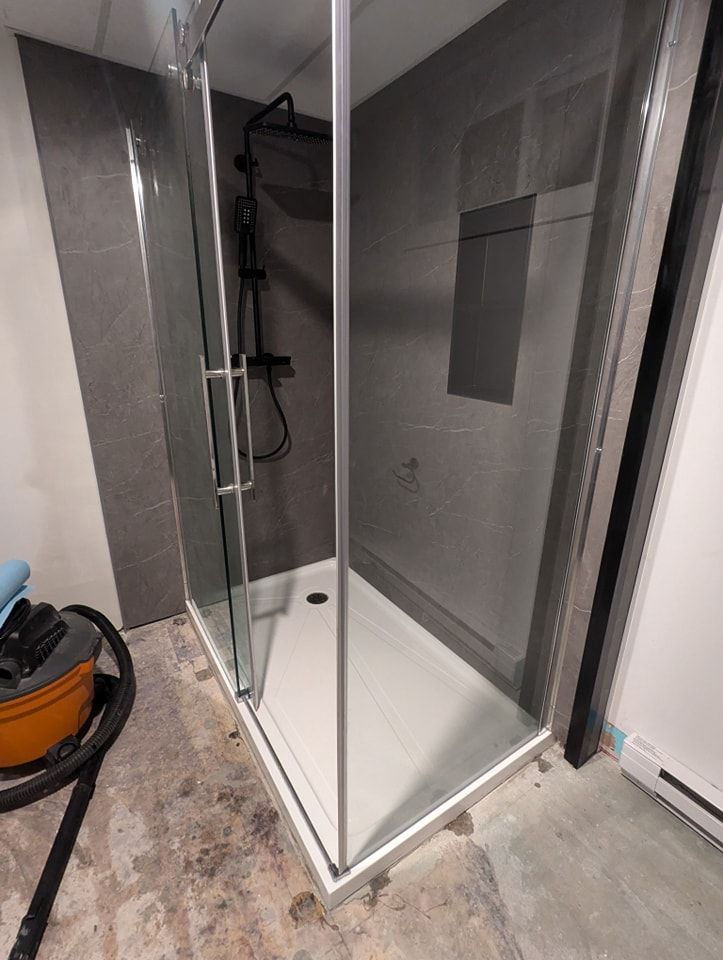 Une salle de bain avec une cabine de douche et un aspirateur.