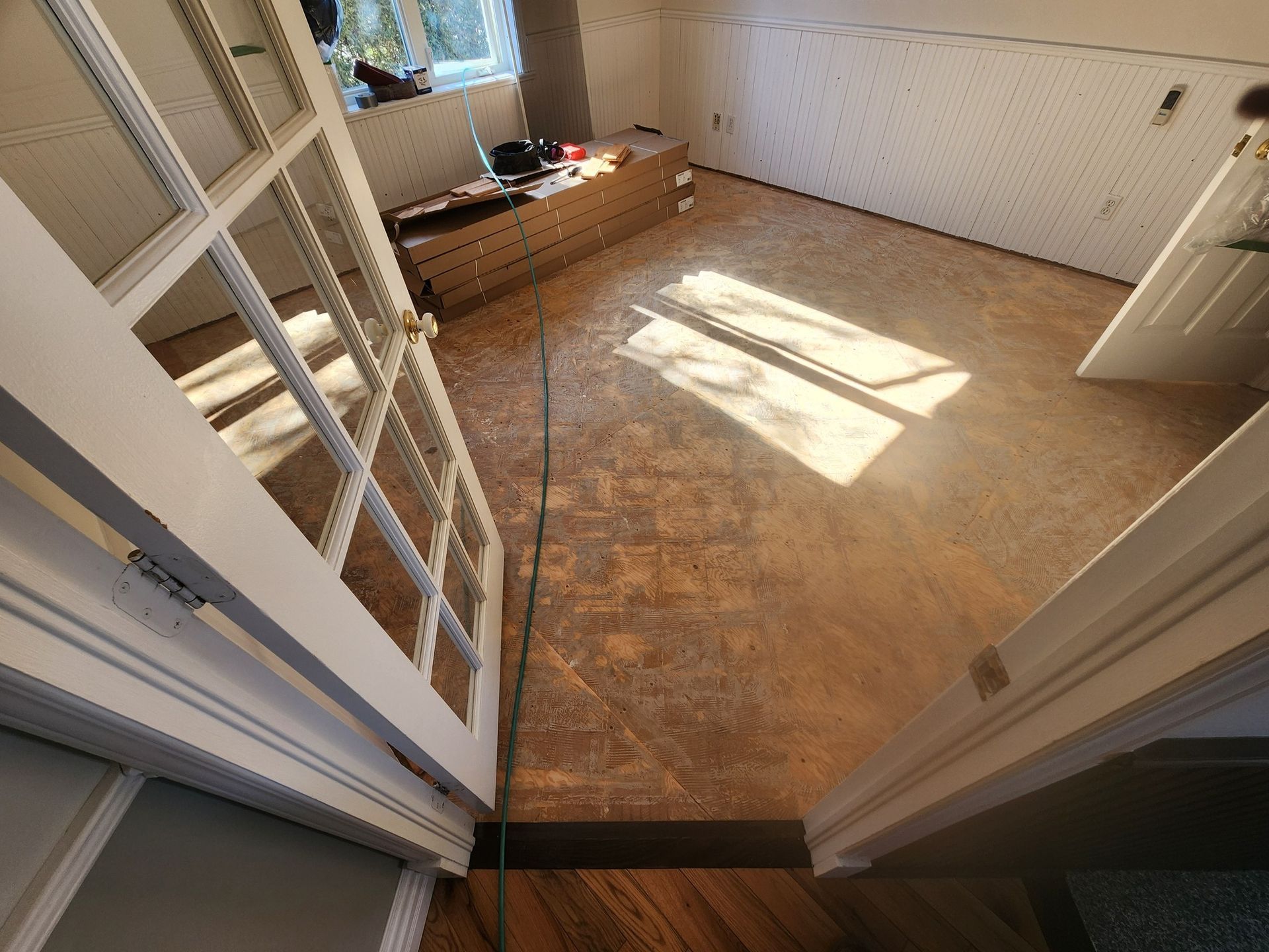 Une pièce avec un plancher en bois et une porte blanche.