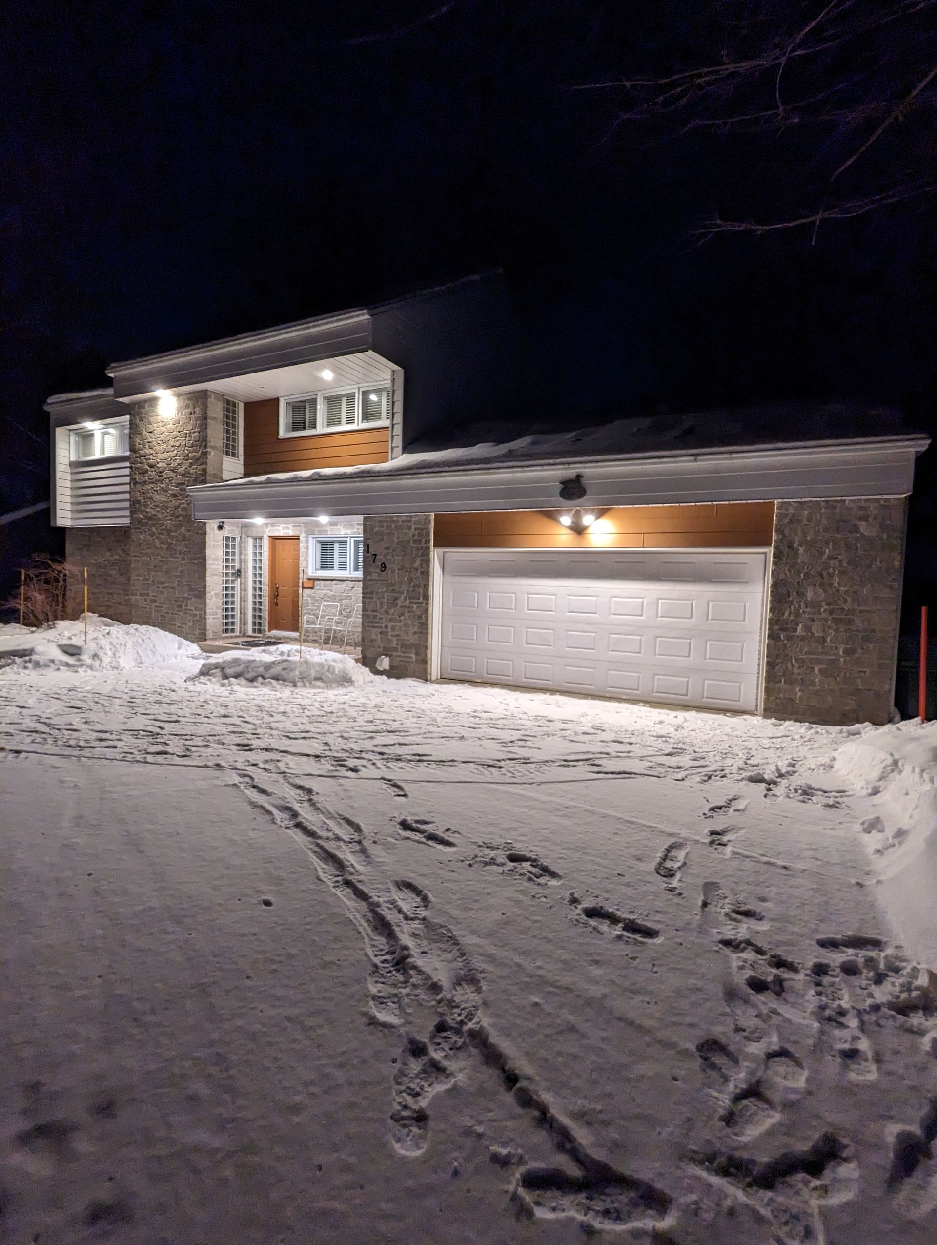 Une grande maison est recouverte de neige la nuit.