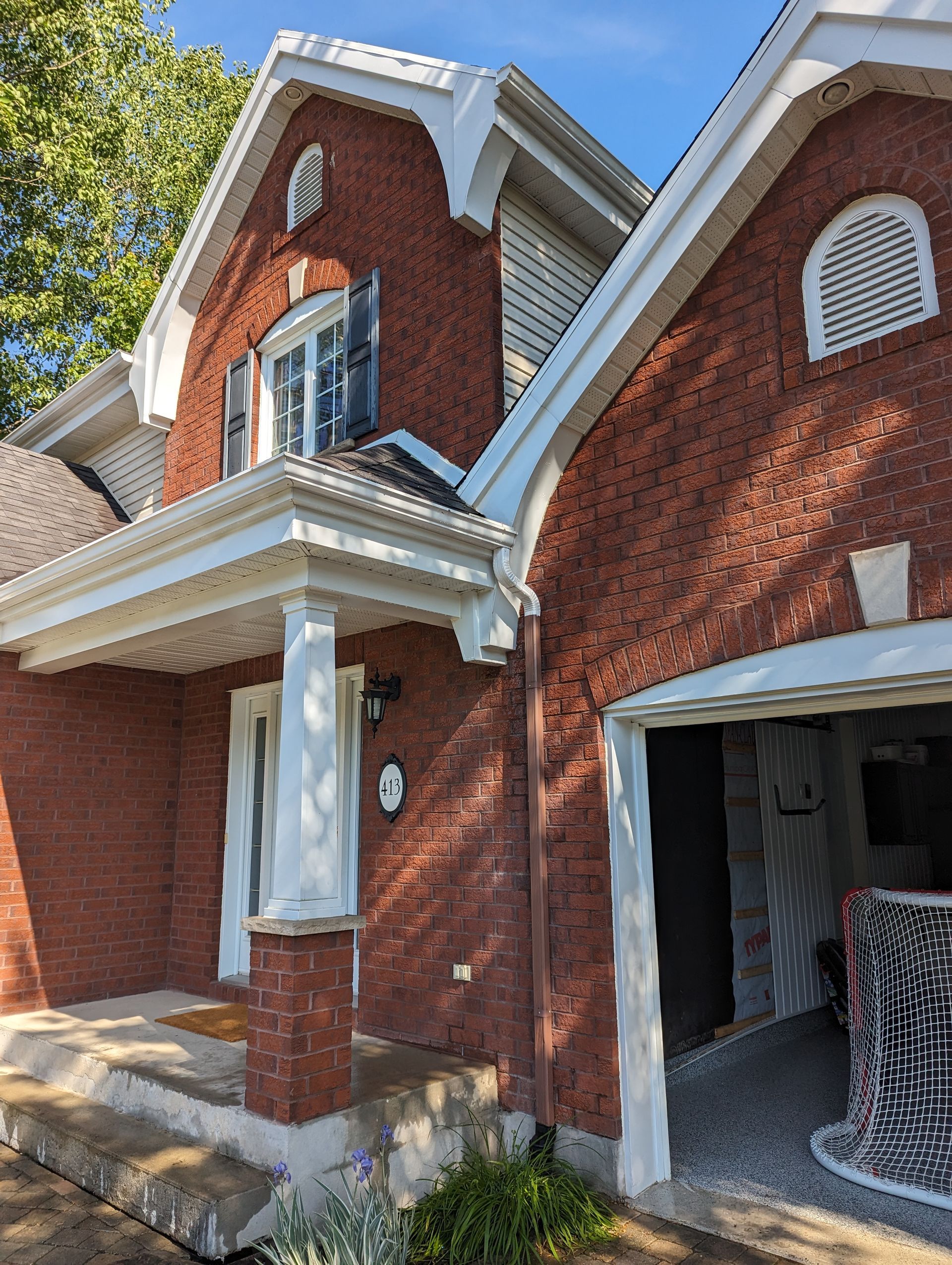 Une grande maison en briques rouges avec un garage et un porche.