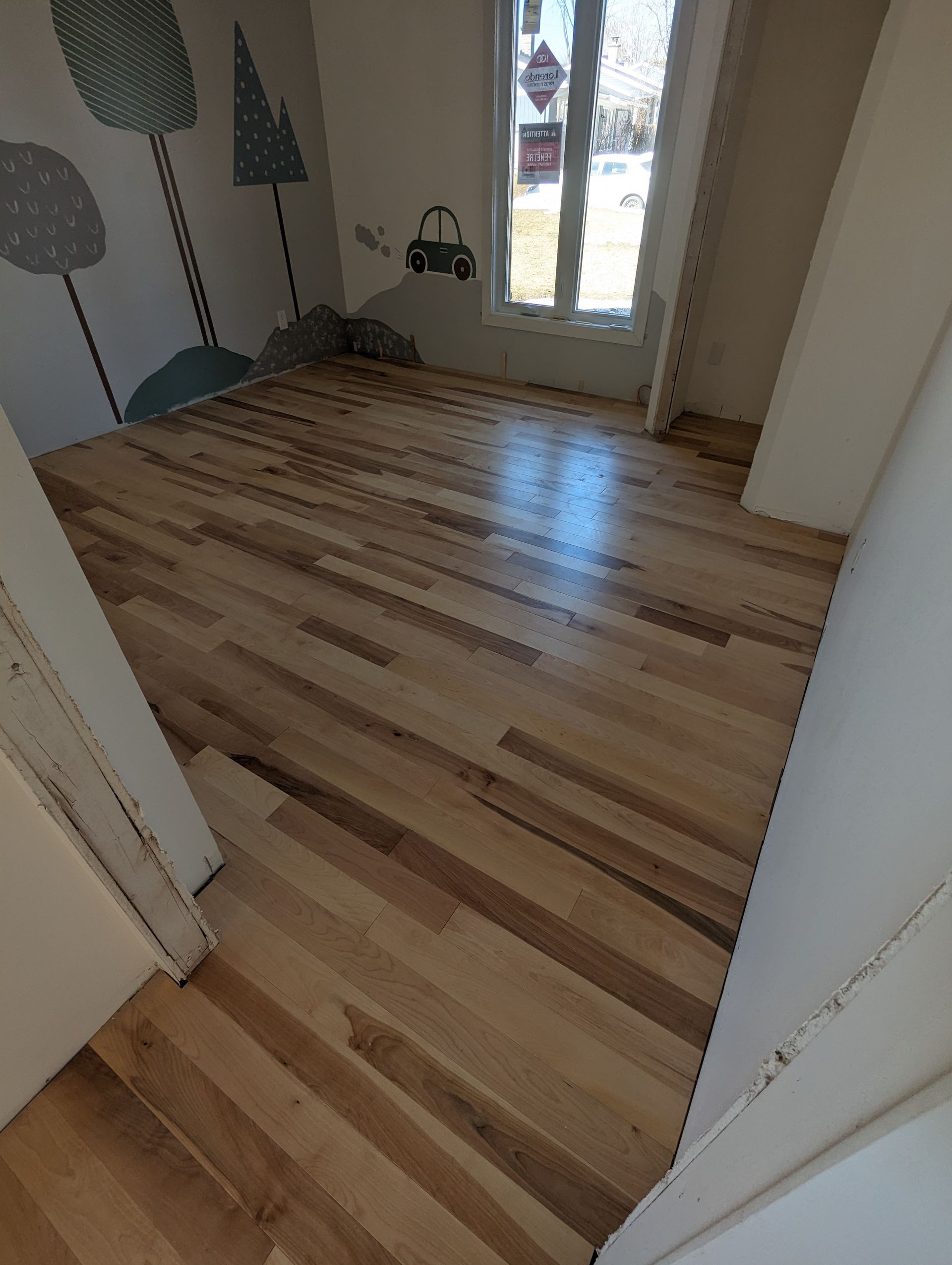 Une pièce avec un plancher en bois et un tableau au mur.