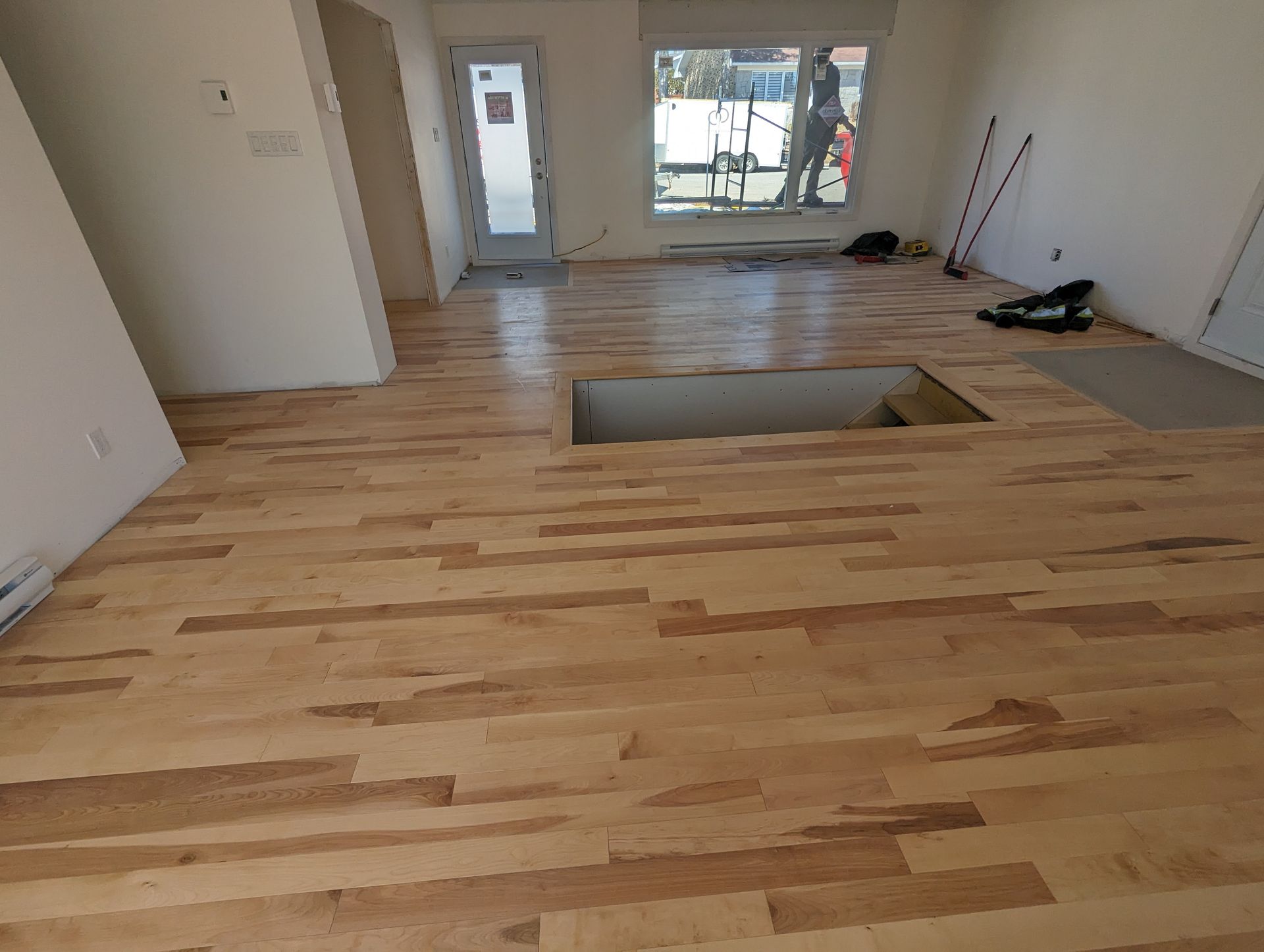 Un salon avec du parquet et un trou dans le sol