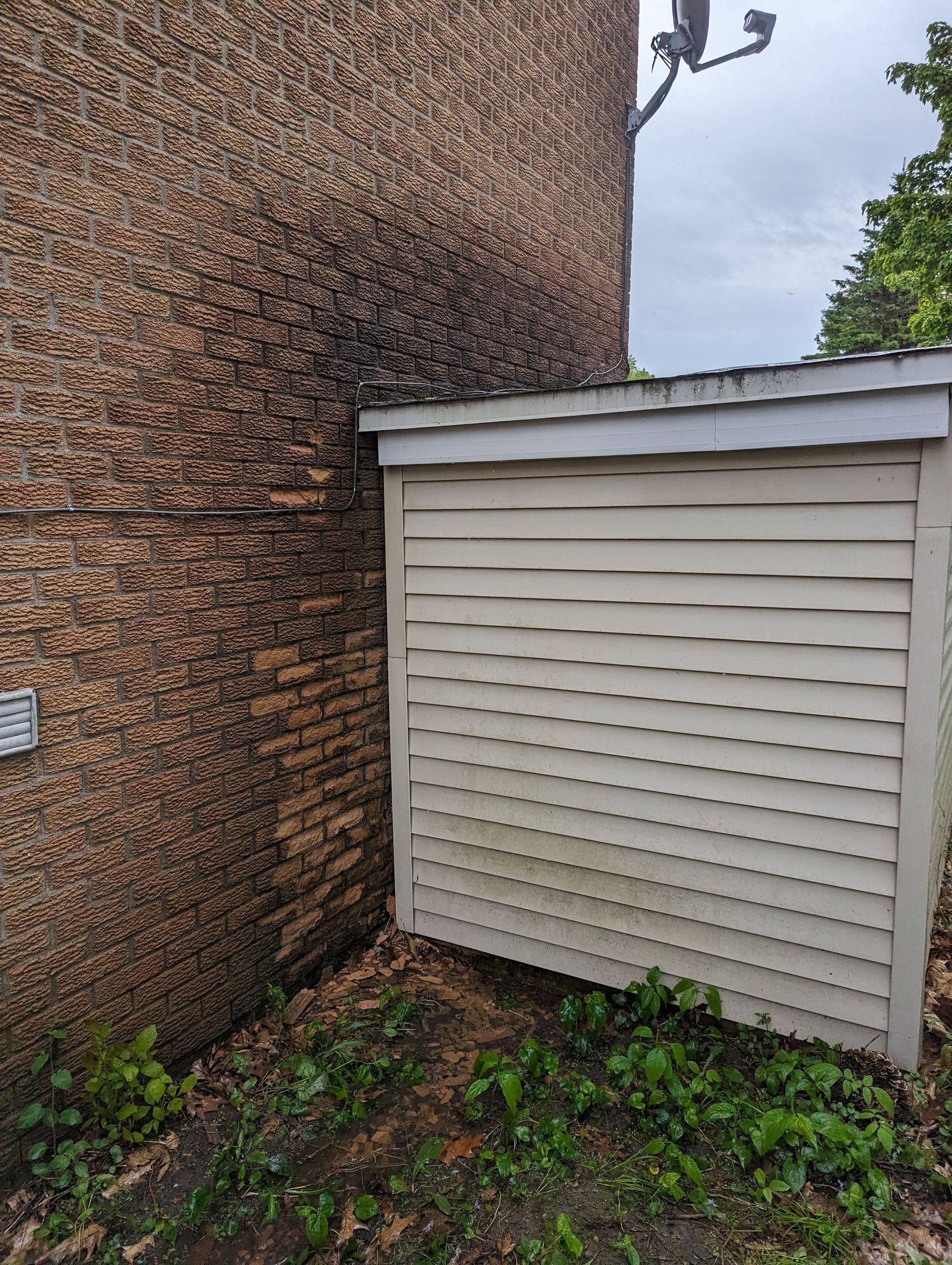 Un hangar blanc est assis à côté d'un mur de briques.