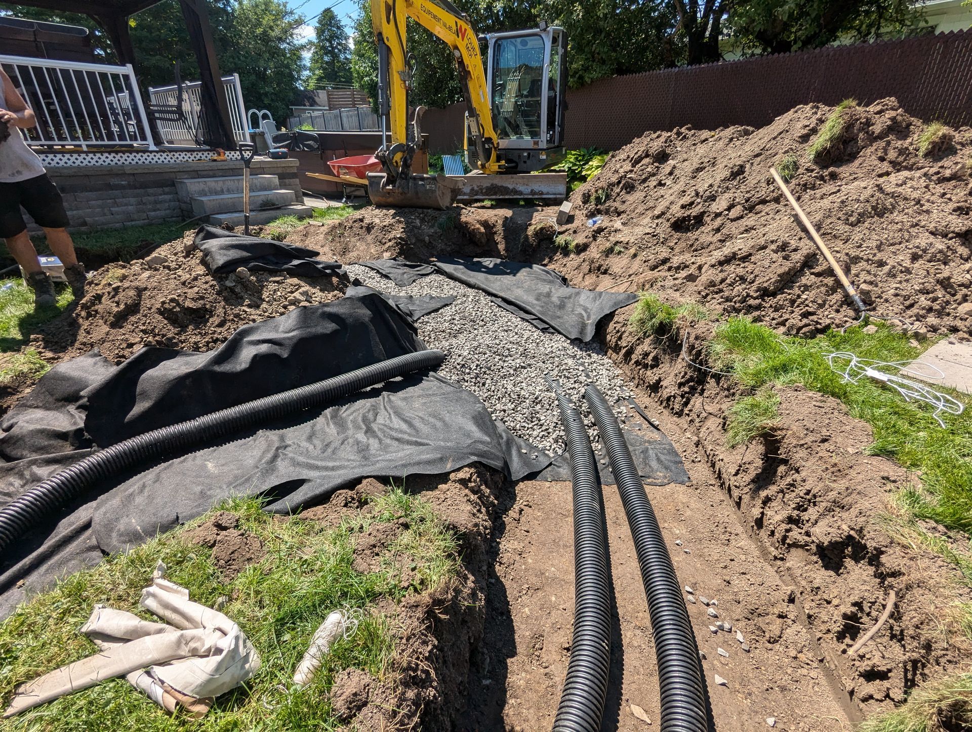Une excavatrice jaune creuse une tranchée dans la terre.