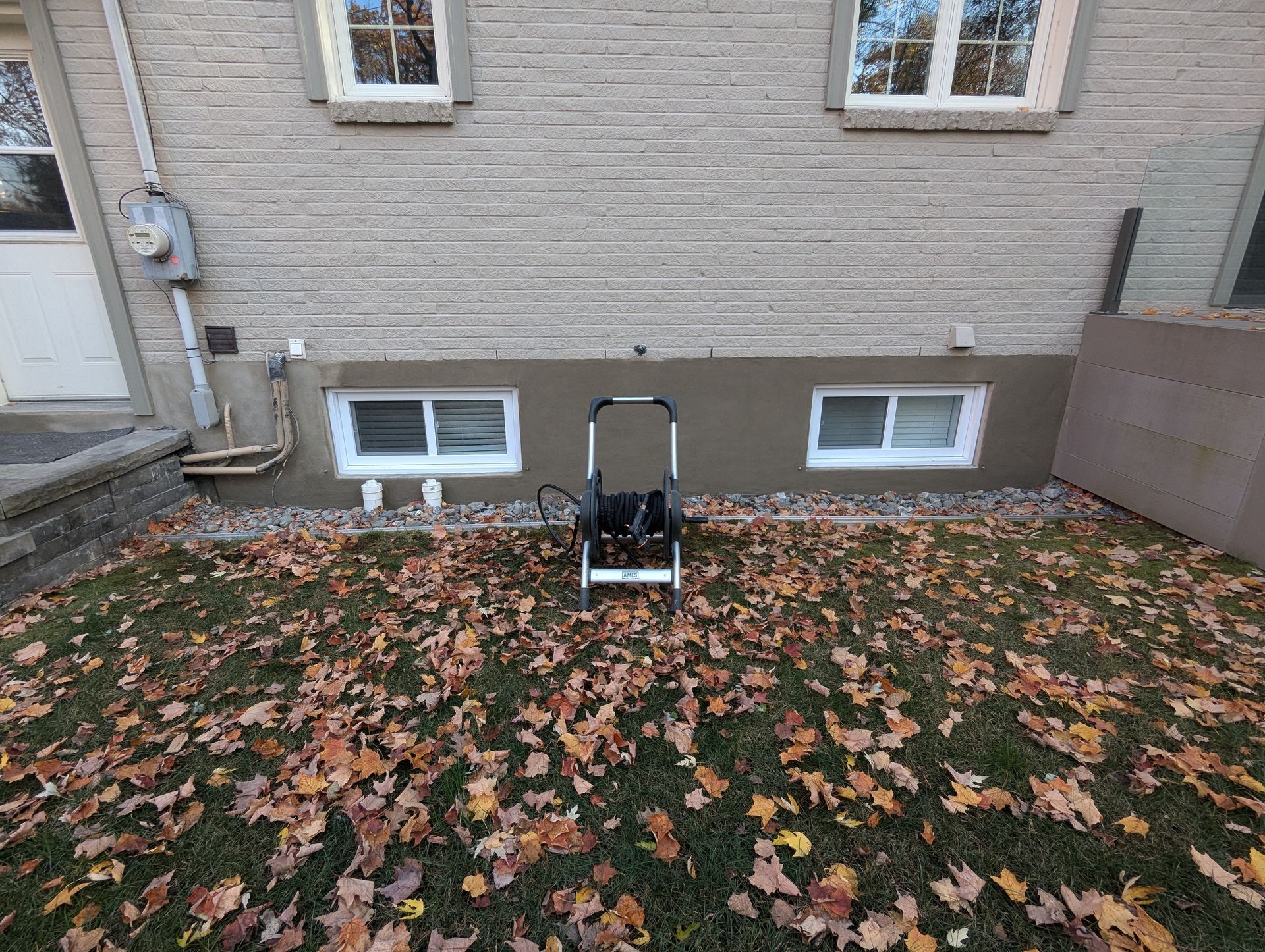 Une brouette est assise dans l'herbe devant une maison.