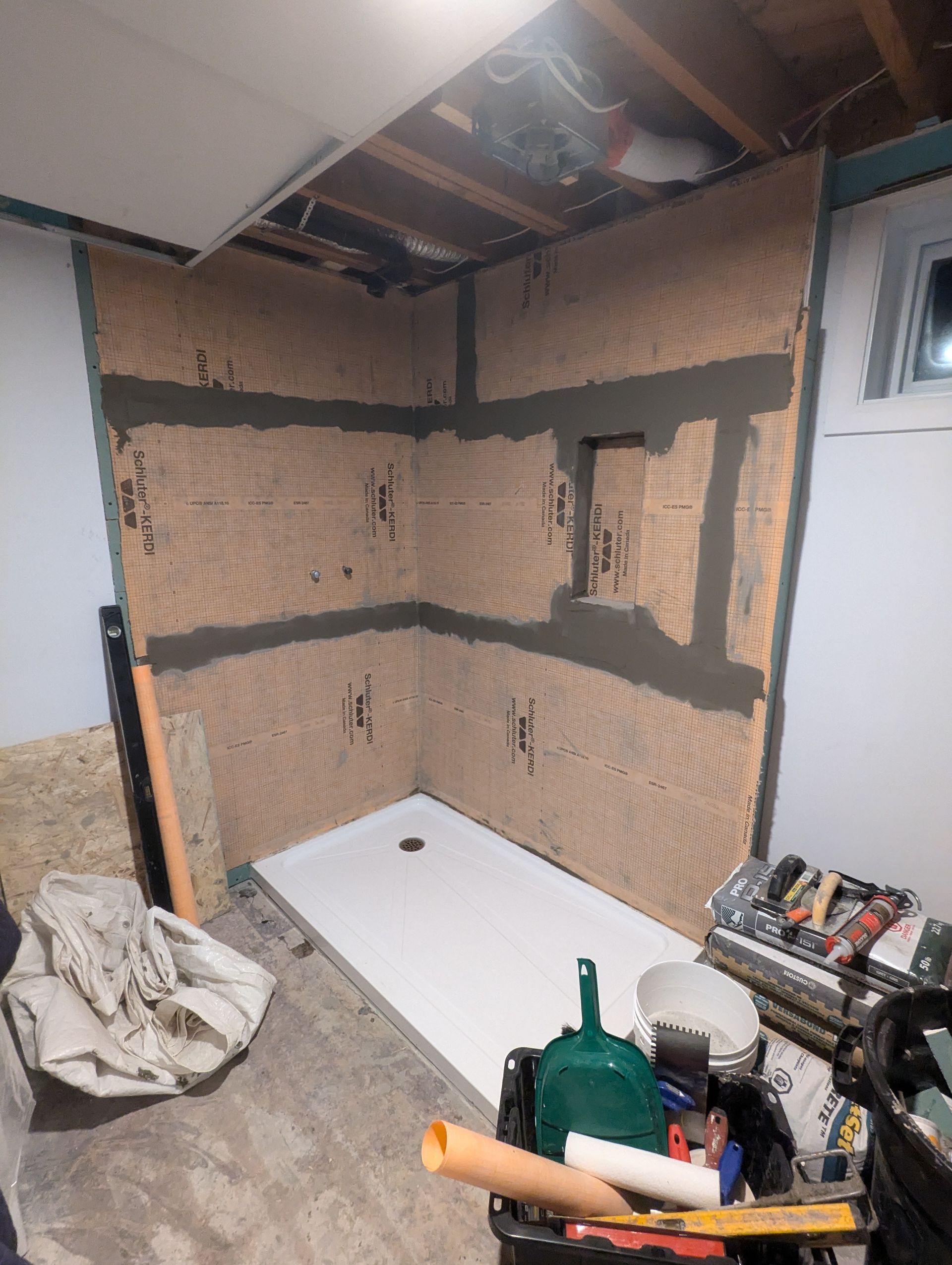 Une pièce avec une cabine de douche et beaucoup d'outils au sol.