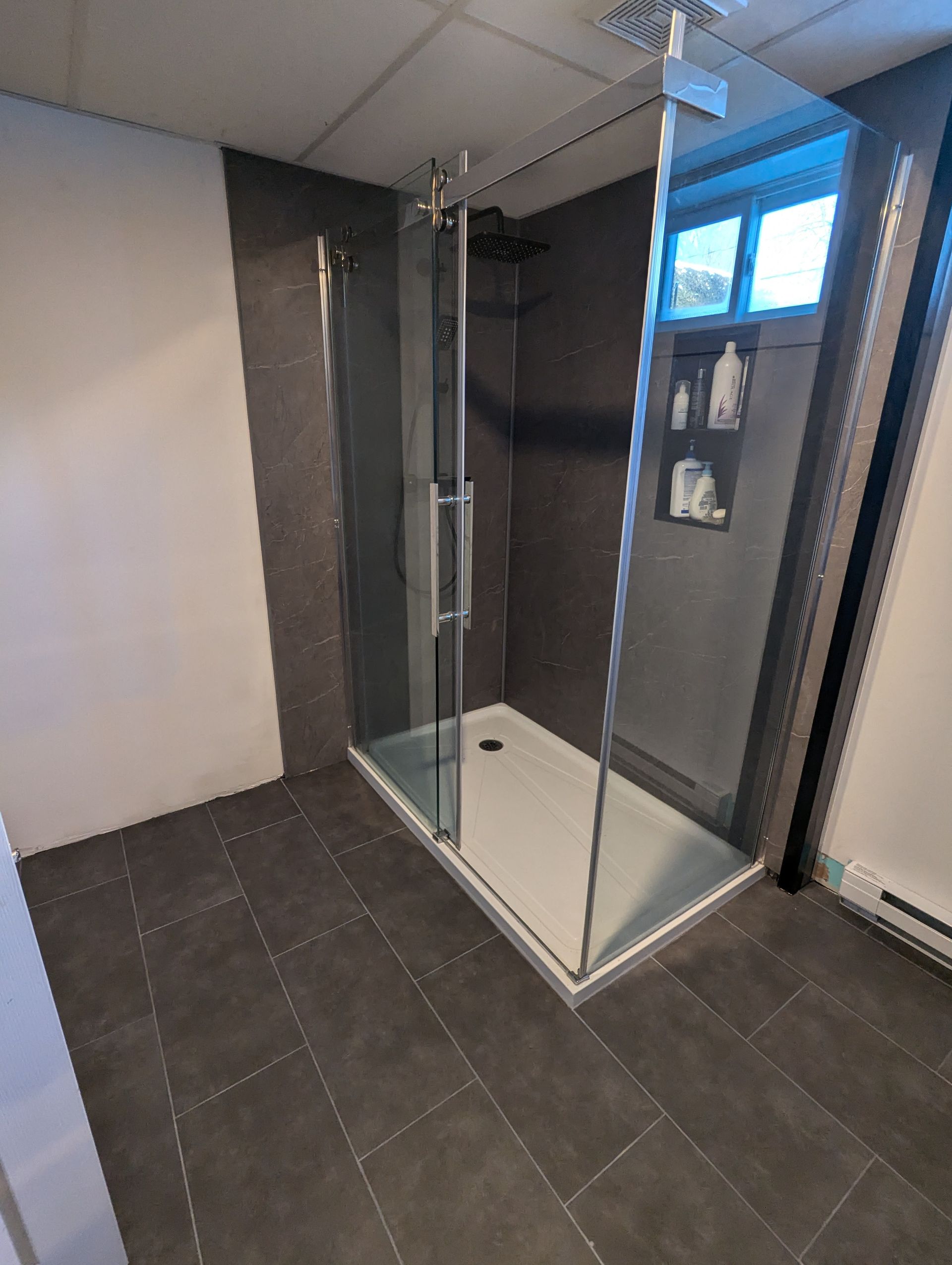 Une salle de bain avec douche à l'italienne avec portes coulissantes en verre.