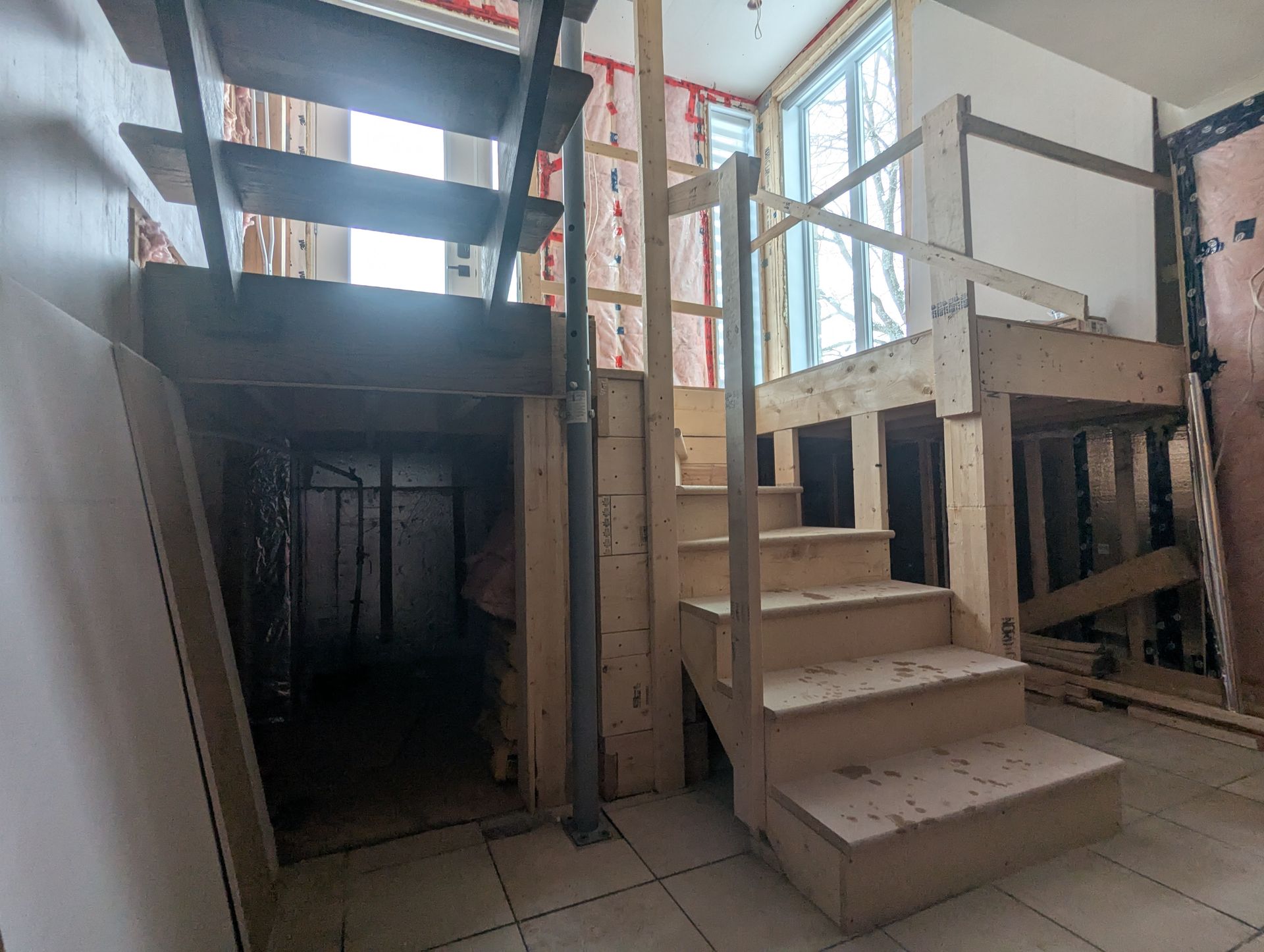 Un escalier en bois menant à un sous-sol en construction.