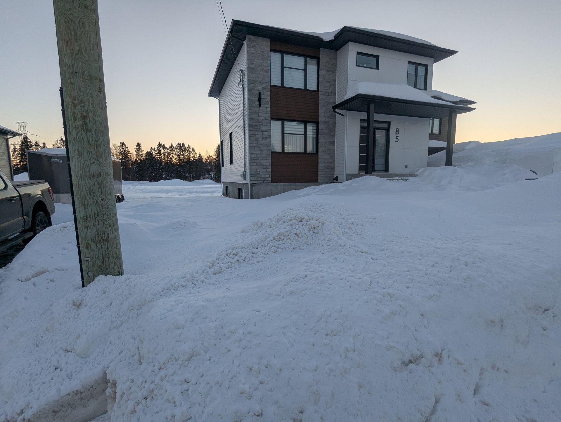 Une maison est recouverte de neige et un camion est garé devant elle.