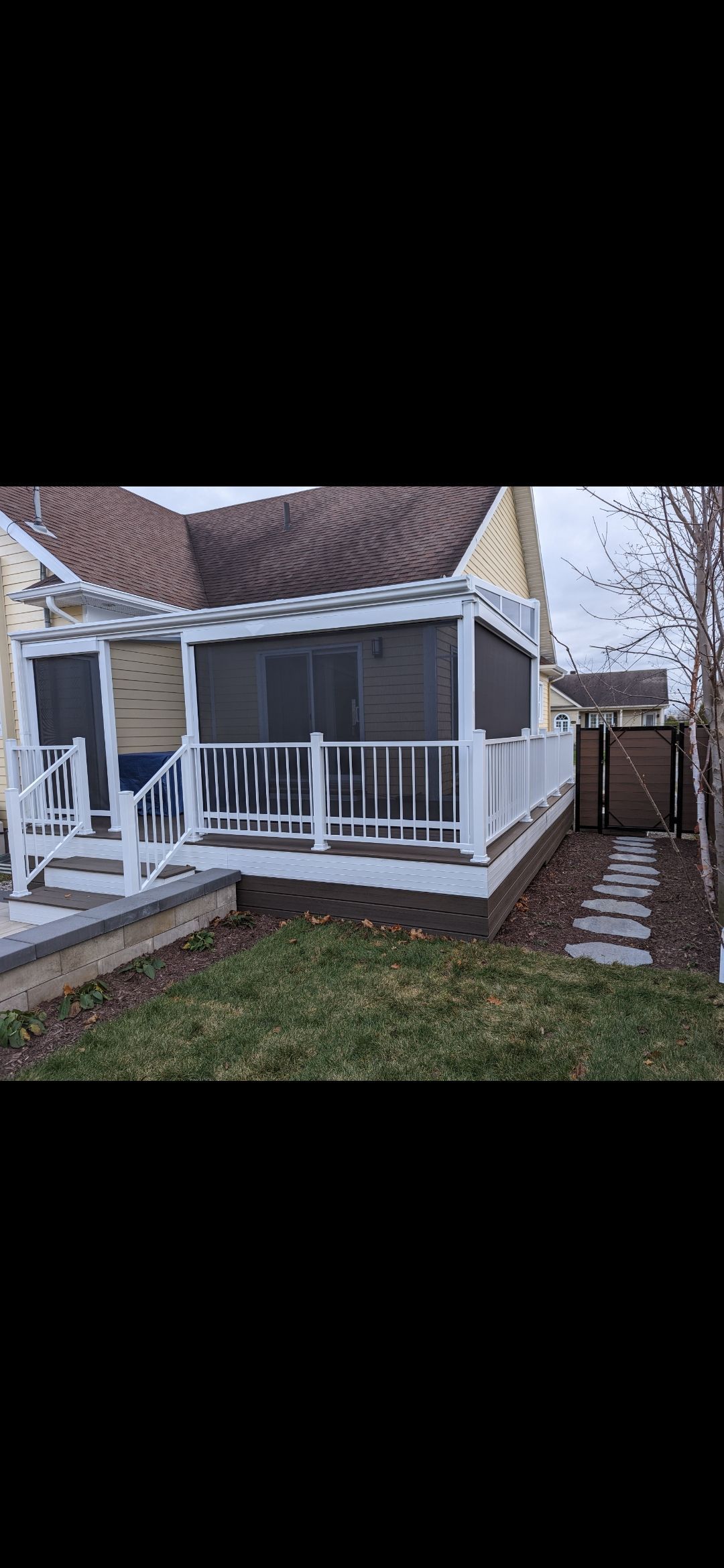 Une maison avec un porche grillagé et une passerelle qui y mène.