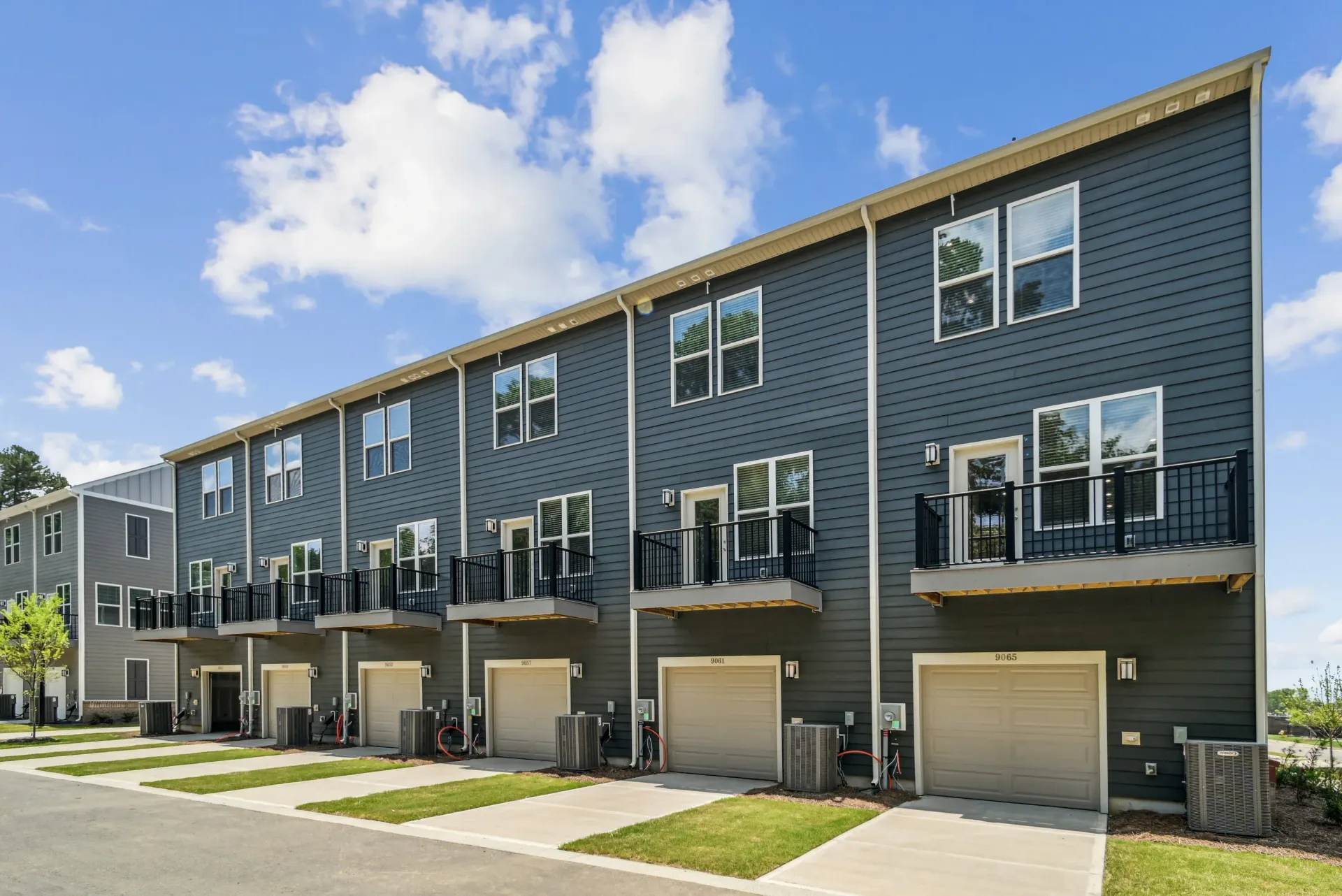 Row of modern townhome-style apartment buildings with garages and balconies.