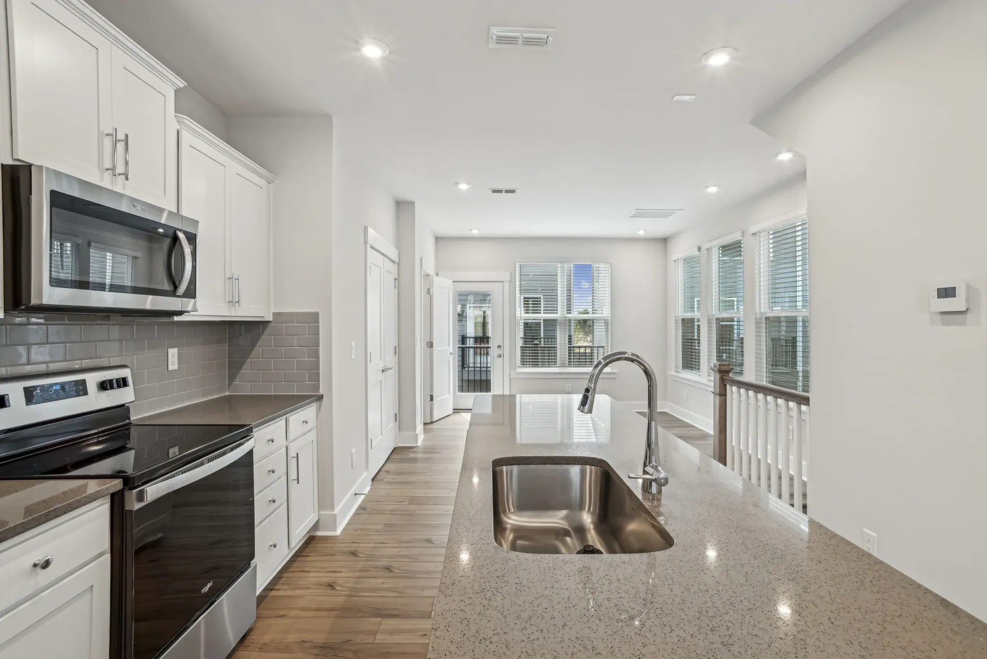 Modern kitchen with an island, stainless steel appliances, white cabinets, and large windows.