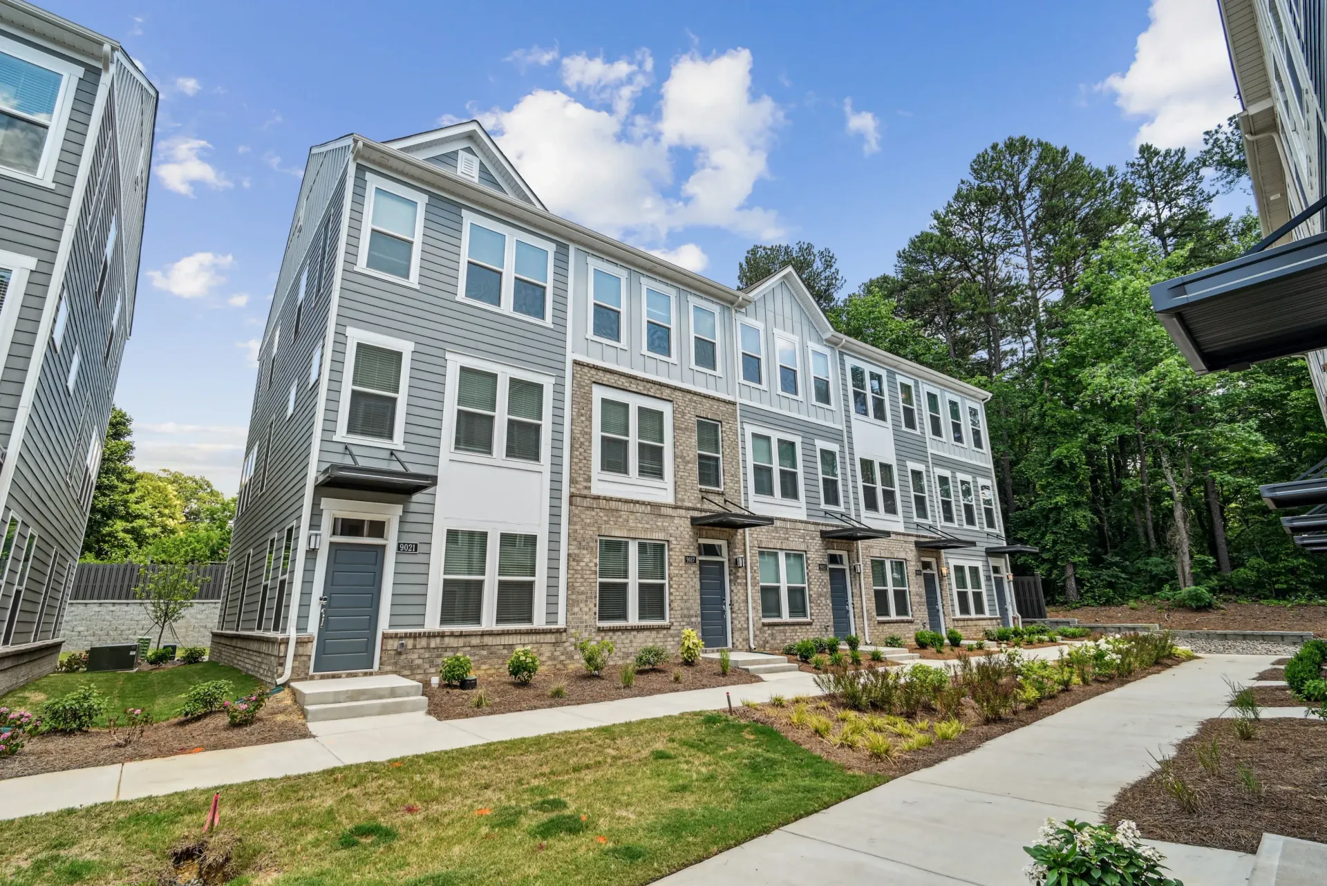 Exterior view of modern gray townhouse-style apartment buildings with landscaped walkways.