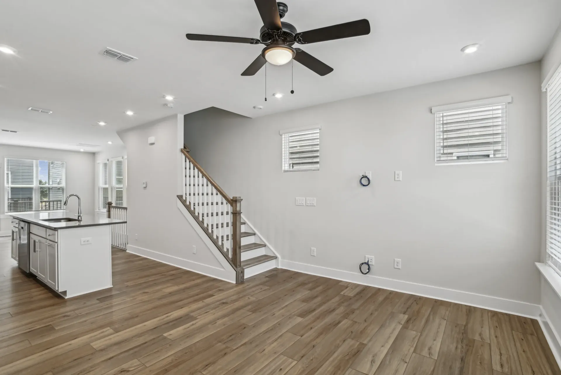 Open-concept living area with kitchen island, staircase, and large windows.