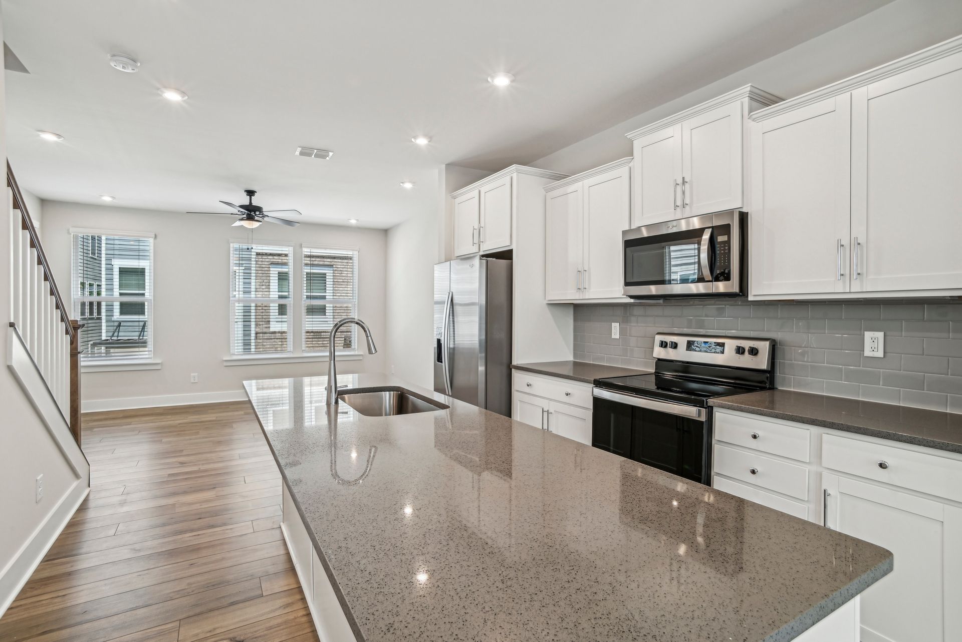 Modern kitchen with white cabinets, stainless steel appliances, and a gray countertop island.