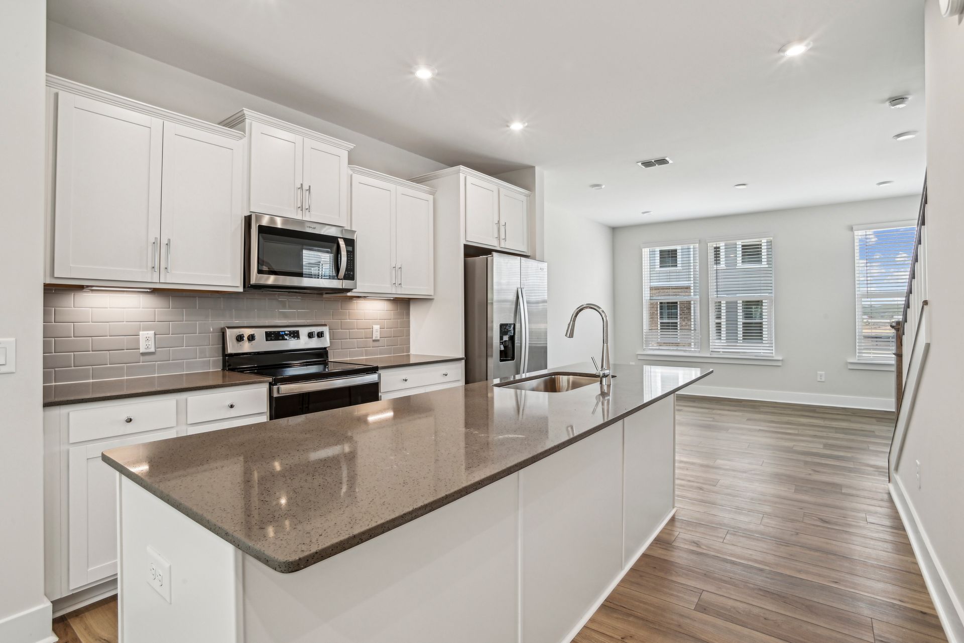 Modern kitchen with white cabinets, stainless steel appliances, and a gray countertop island.