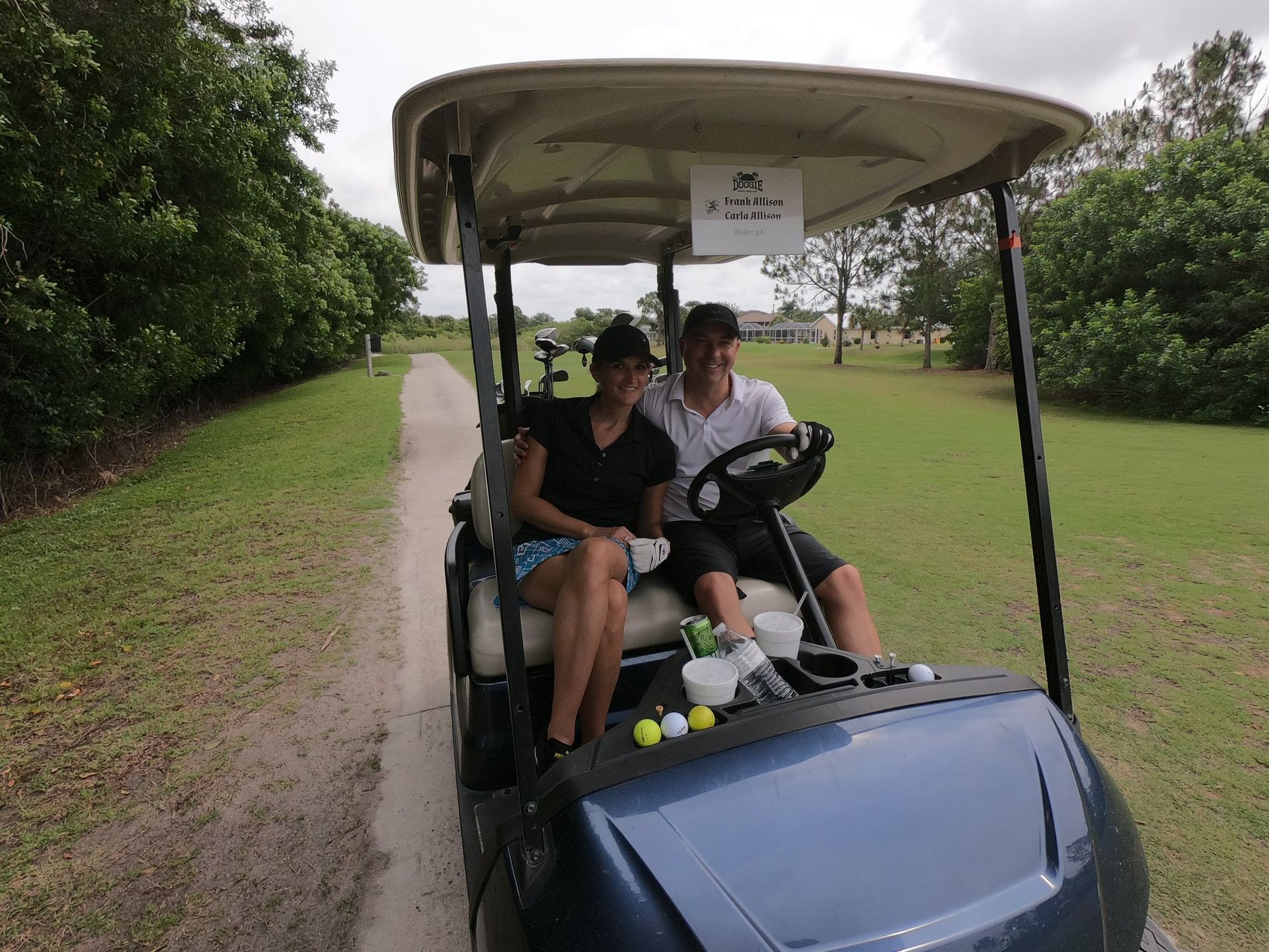 A Man and A Woman Are Sitting in A Golf Cart — North Port, FL — Team Doogie