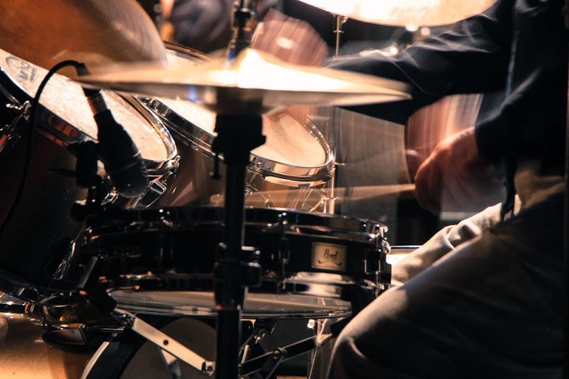 A man is playing a drum set in a dark room