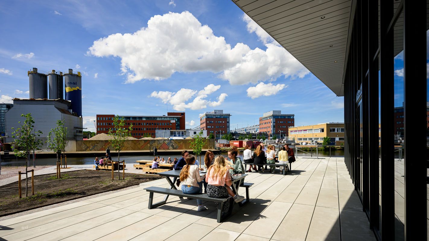 A group of people are sitting at picnic tables on a patio.