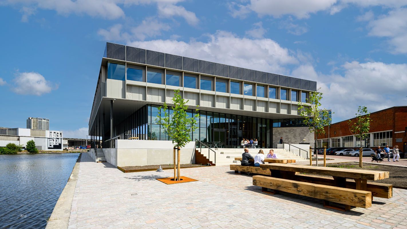 A large building with a lot of windows is next to a body of water.