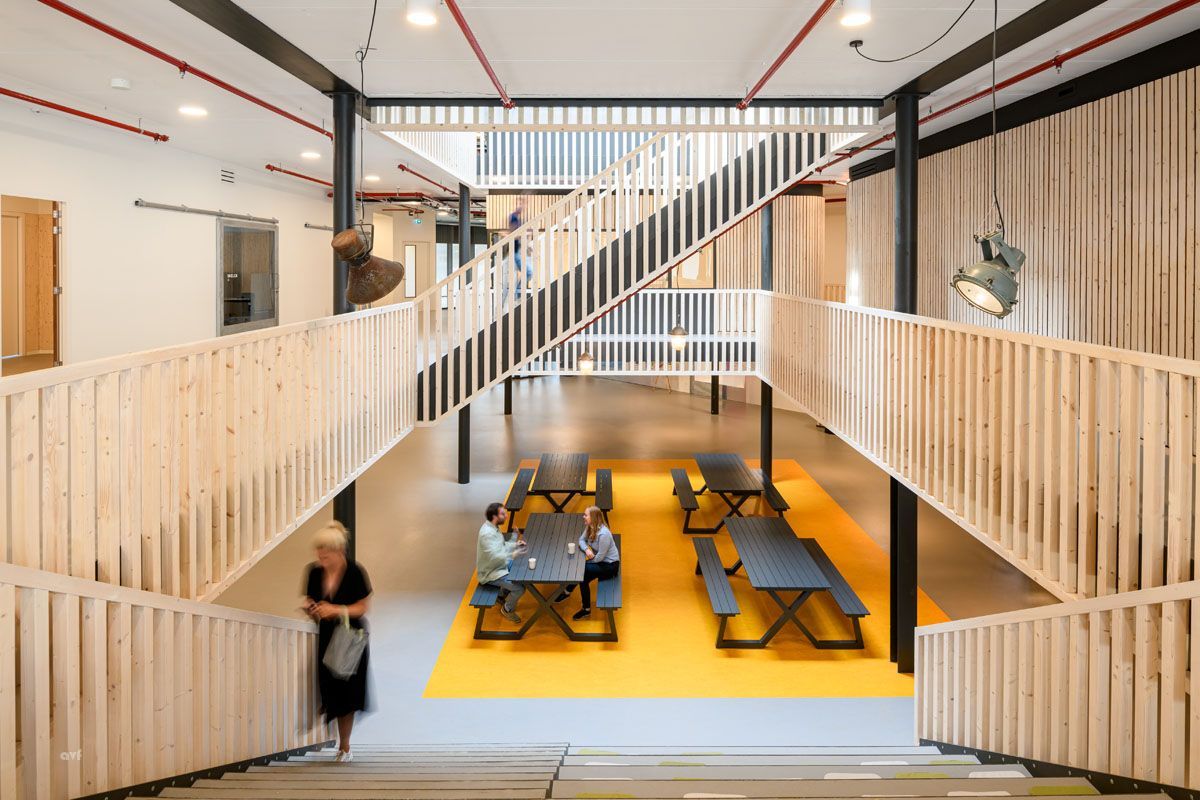 A woman is walking down a set of stairs in a building with tables and benches.