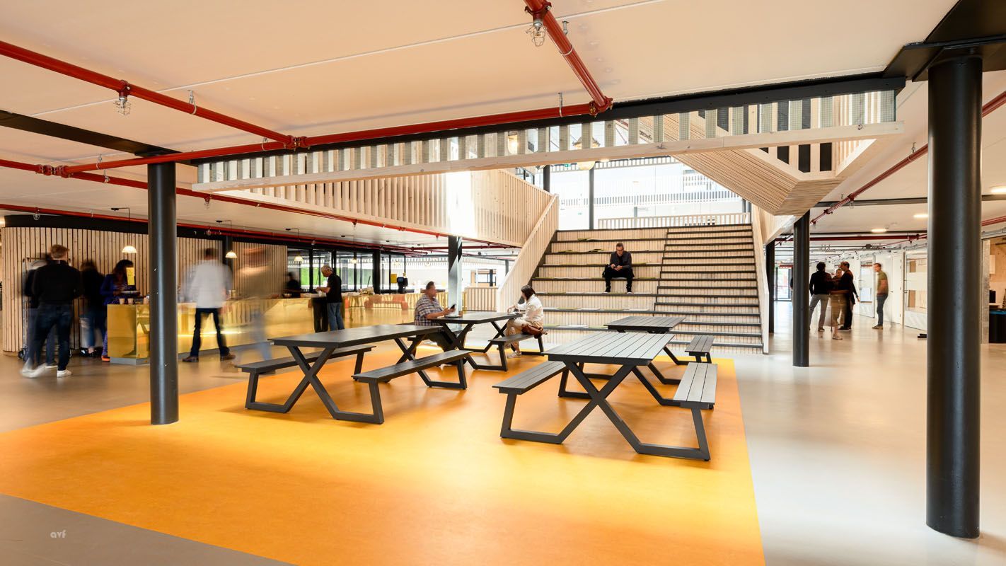 A group of people are sitting at picnic tables in a building.