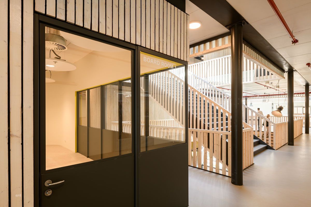 A hallway in a building with stairs and a glass door.