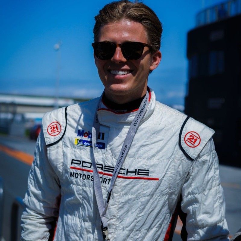 A man wearing sunglasses and a porsche motors jacket
