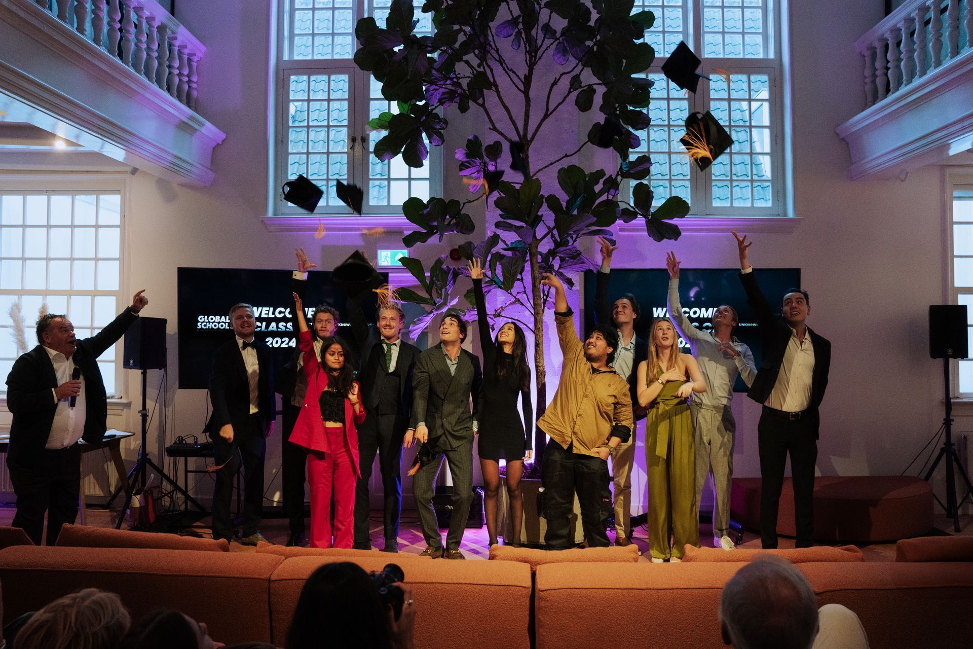 A group of people are standing on a stage throwing their hats in the air.