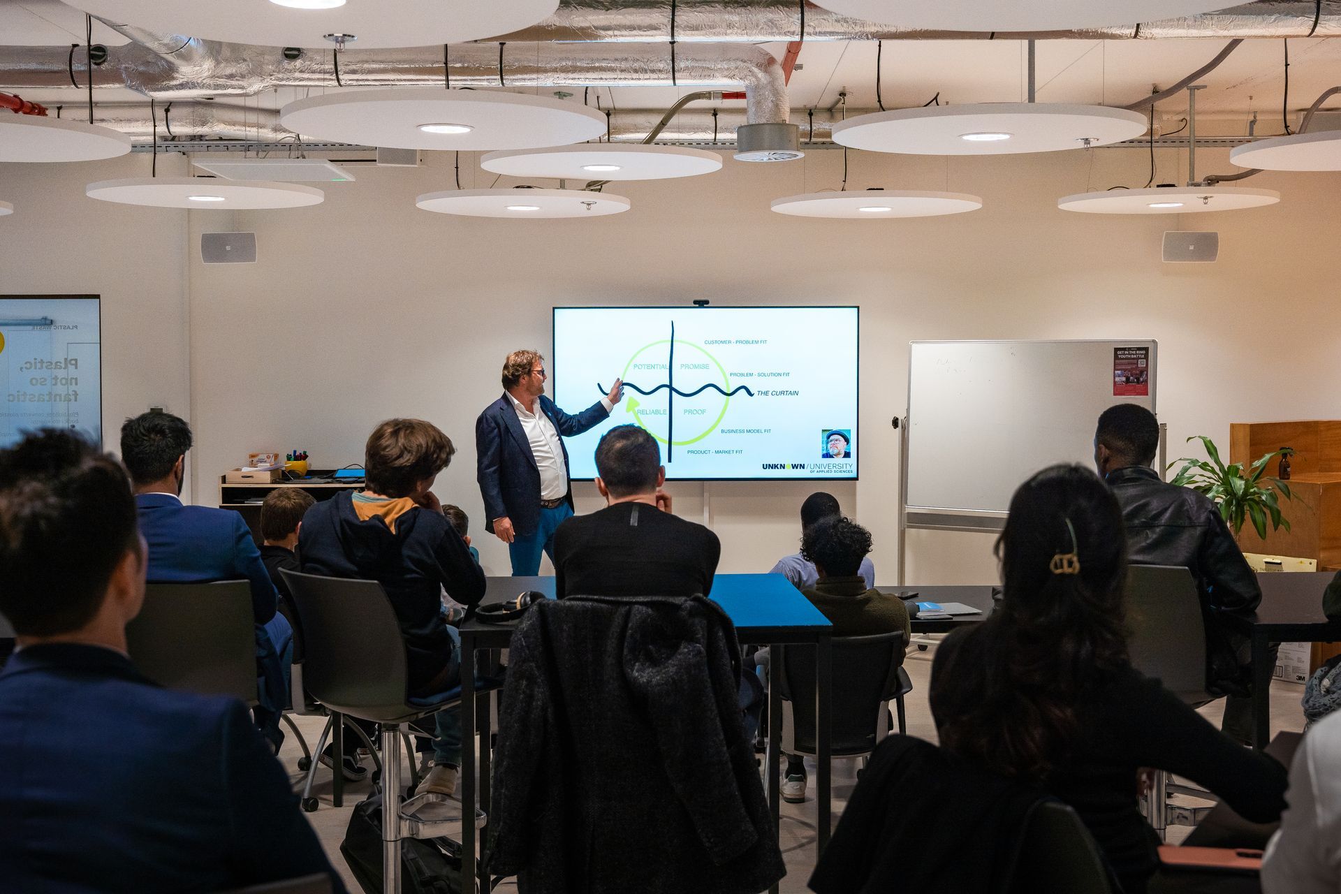 A man is giving a presentation to a group of people in a classroom.