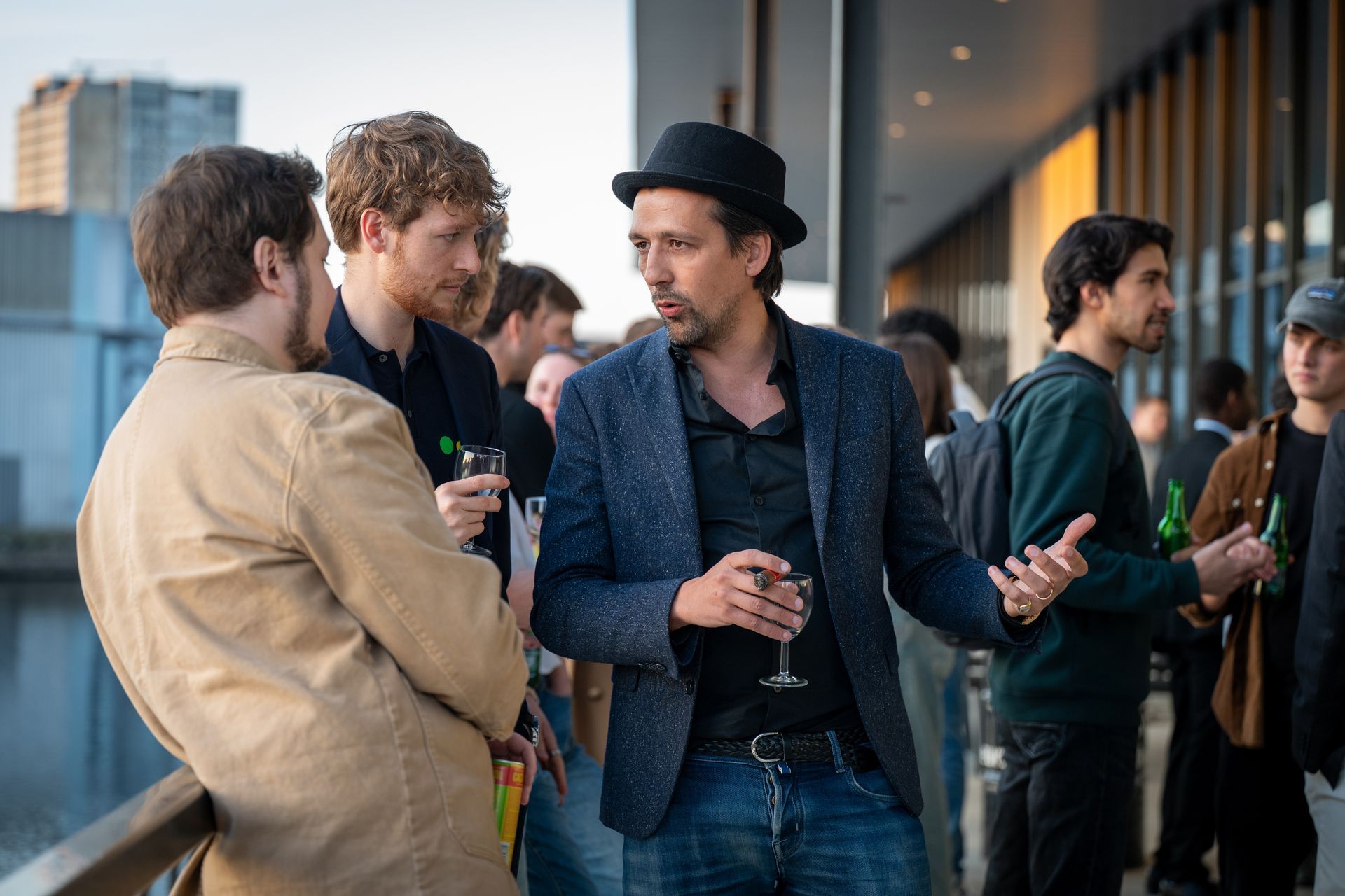 A group of men are standing next to each other talking and drinking wine.