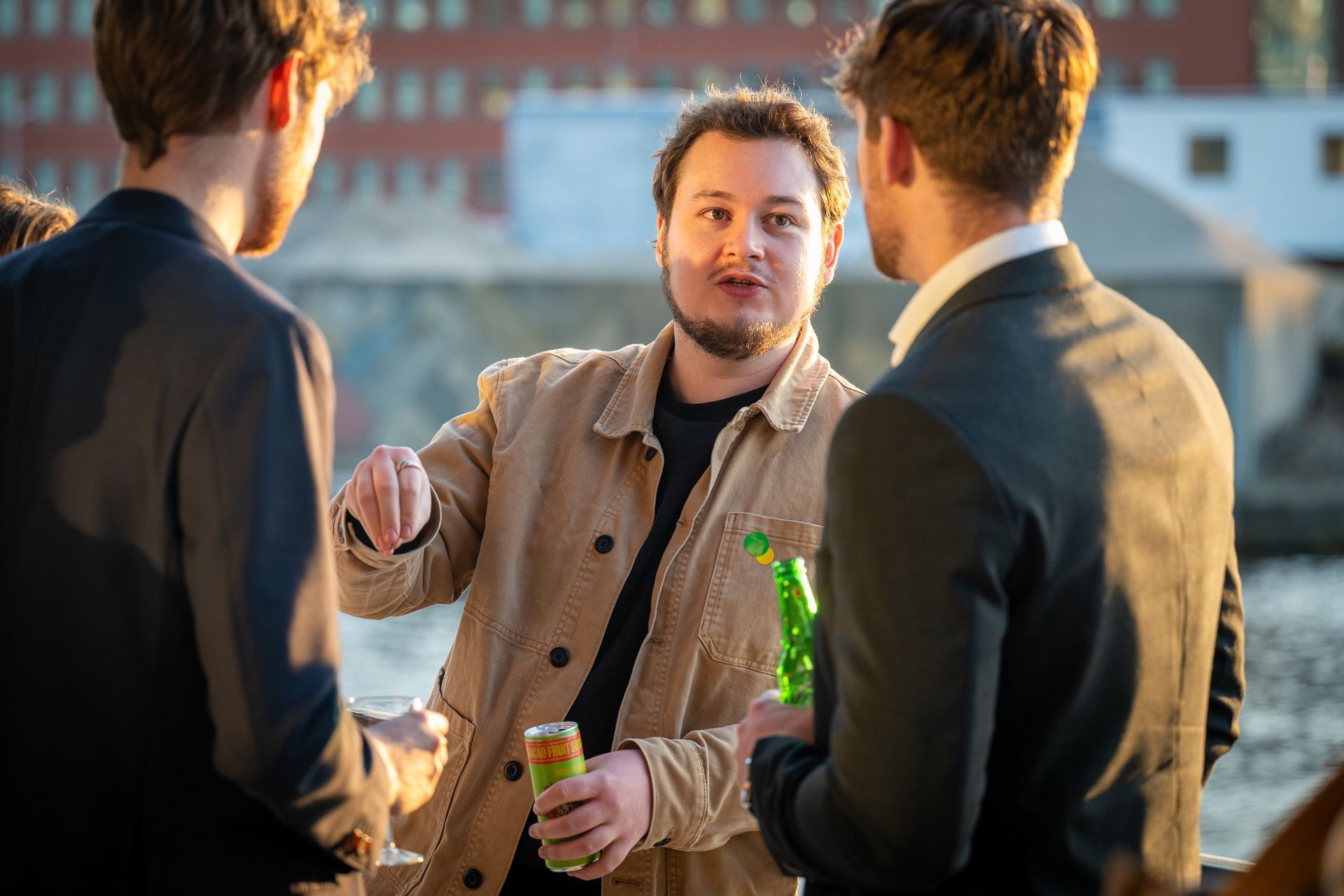A group of men are standing next to each other talking and drinking beer.