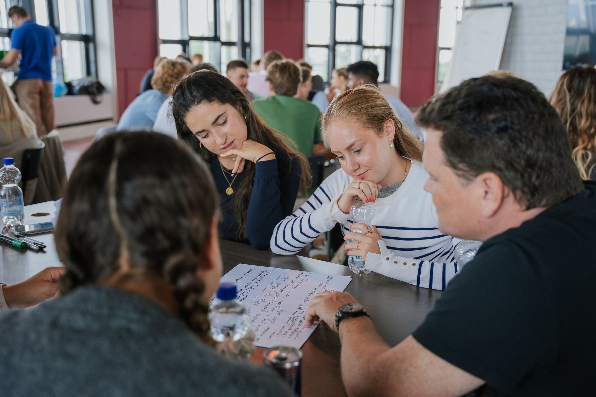 A group of people are standing around a table talking to each other.