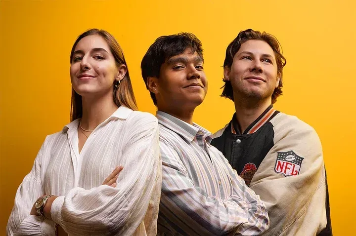 A group of three people standing next to each other on a yellow background.