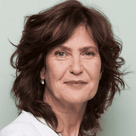 A woman with red hair and a white shirt is smiling for the camera.