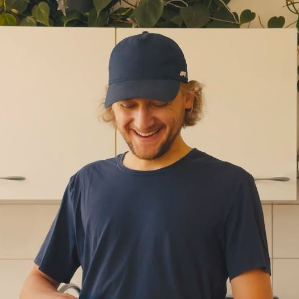 A man wearing a blue hat and a blue shirt is smiling