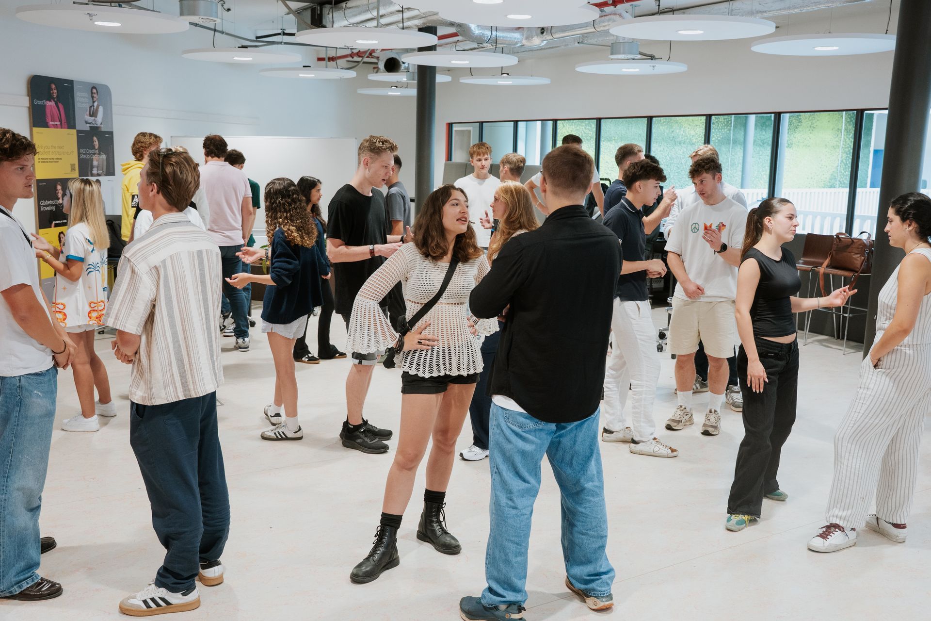 A group of people are sitting on benches in front of a large building.