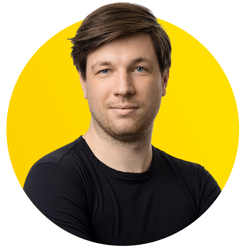 A man in a black shirt is standing in front of a yellow circle.
