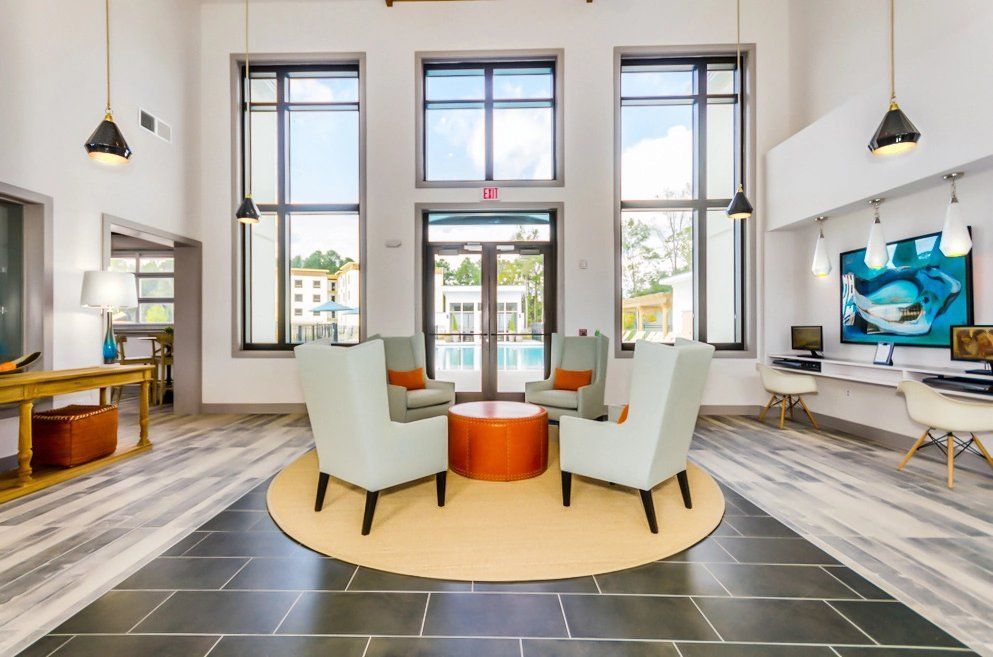 A community room with chairs , a table , and a large window.