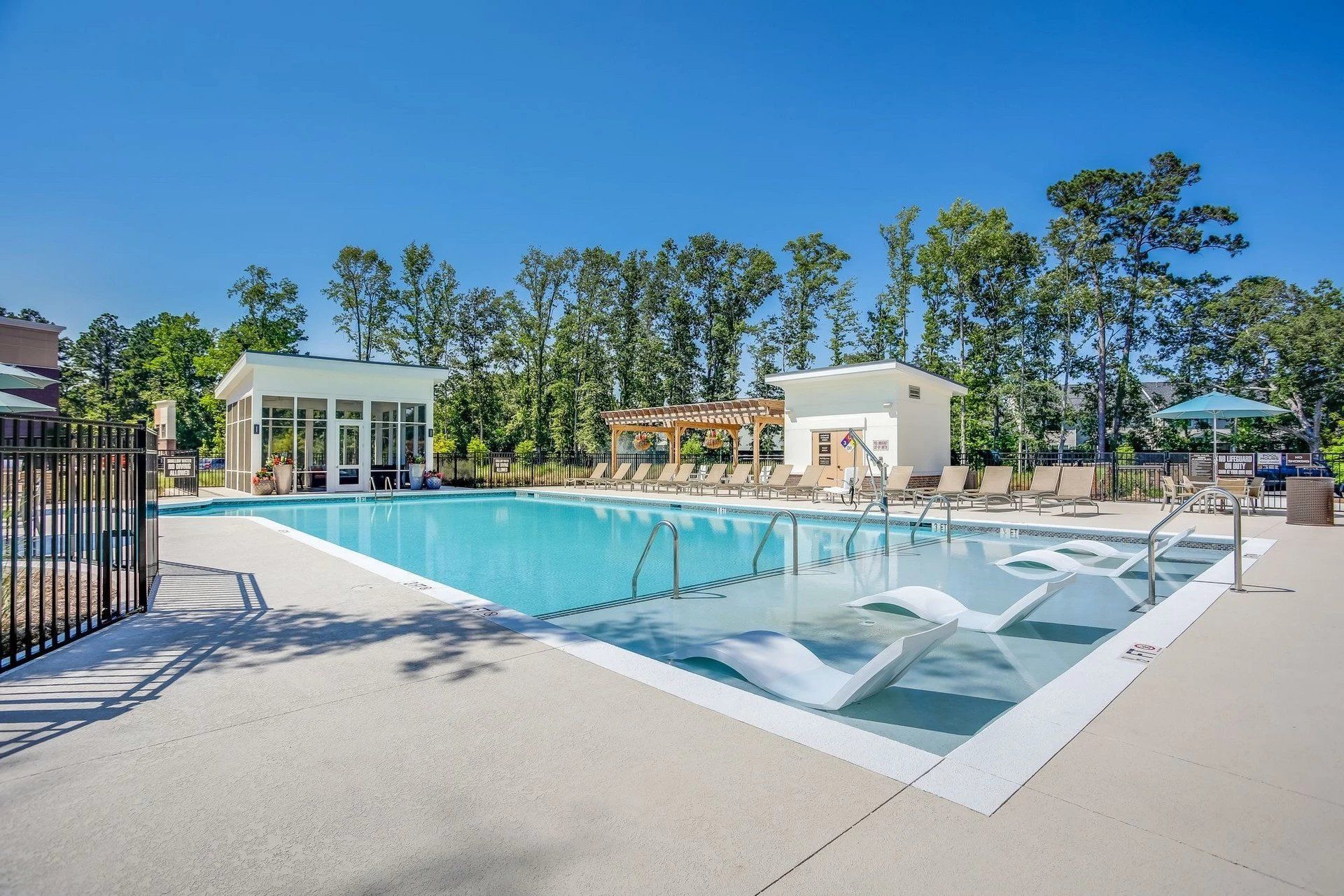 A large swimming pool surrounded by chairs and a fence.