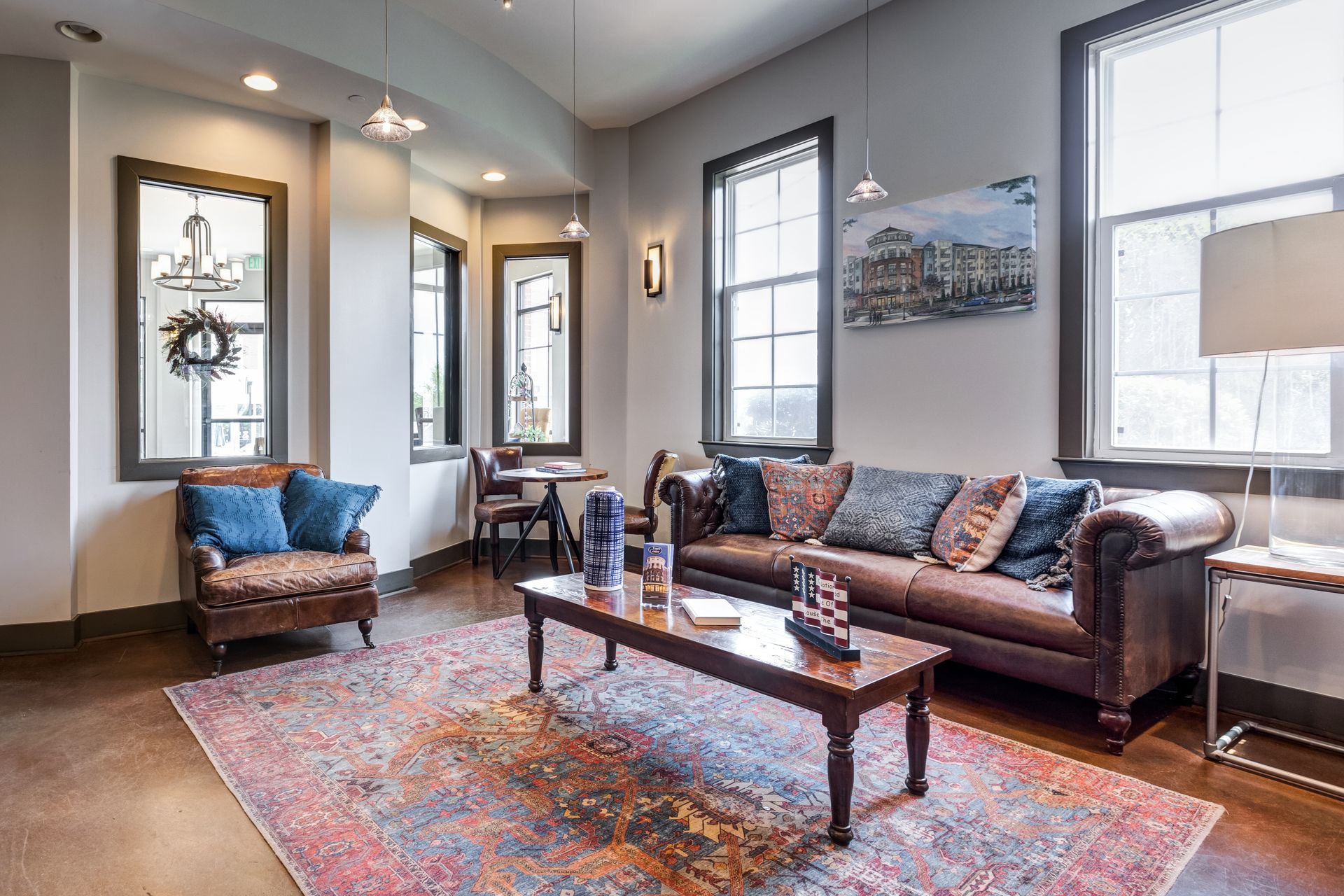 Living room with brown leather sofa, rug, windows, and armchair at Town Center at Lake Carolina in Columbia, SC.