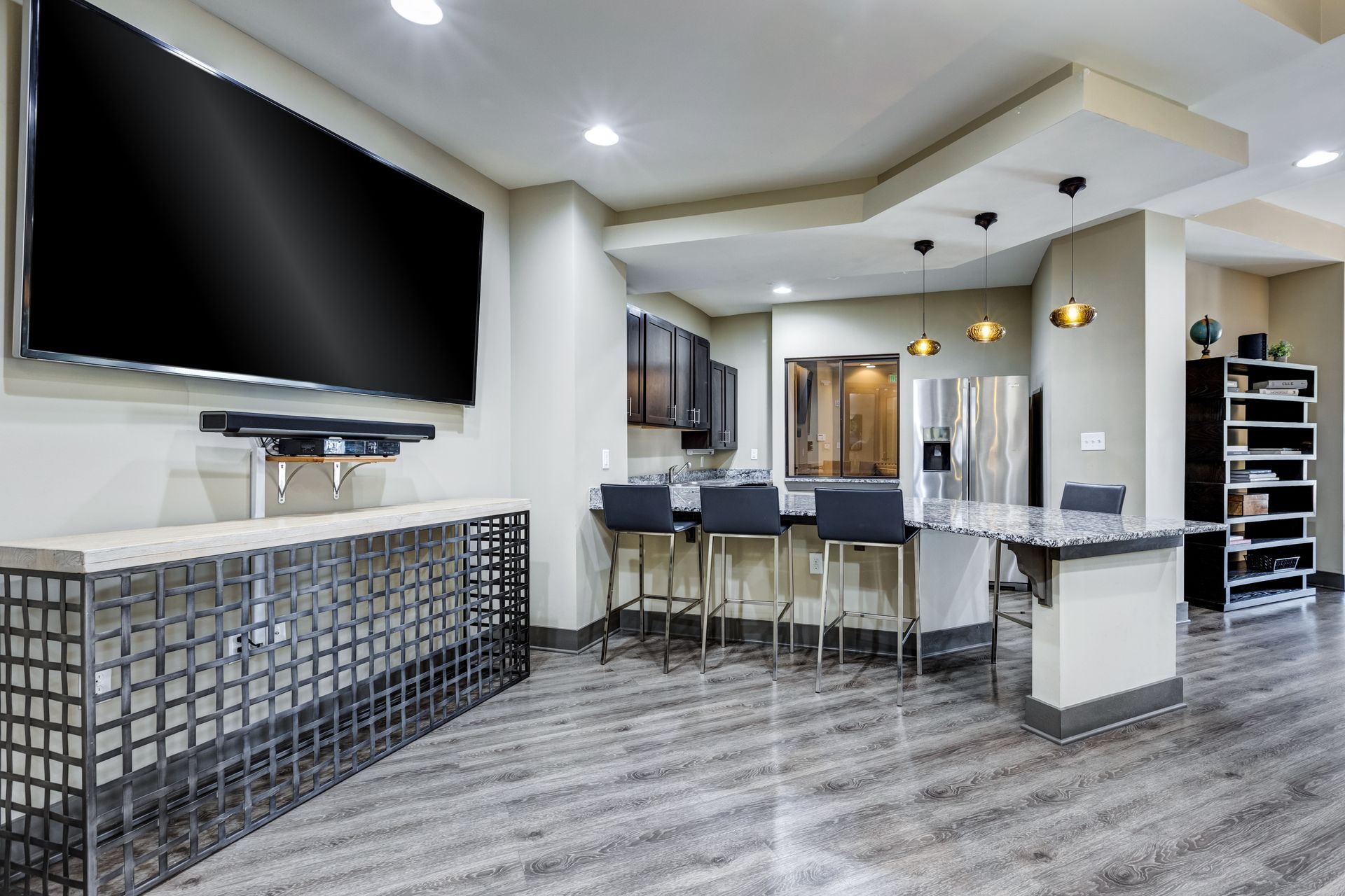 Spacious, modern basement with a large TV, bar, and kitchen area. Gray and neutral tones throughout at Town Center at Lake Carolina in Columbia, SC.