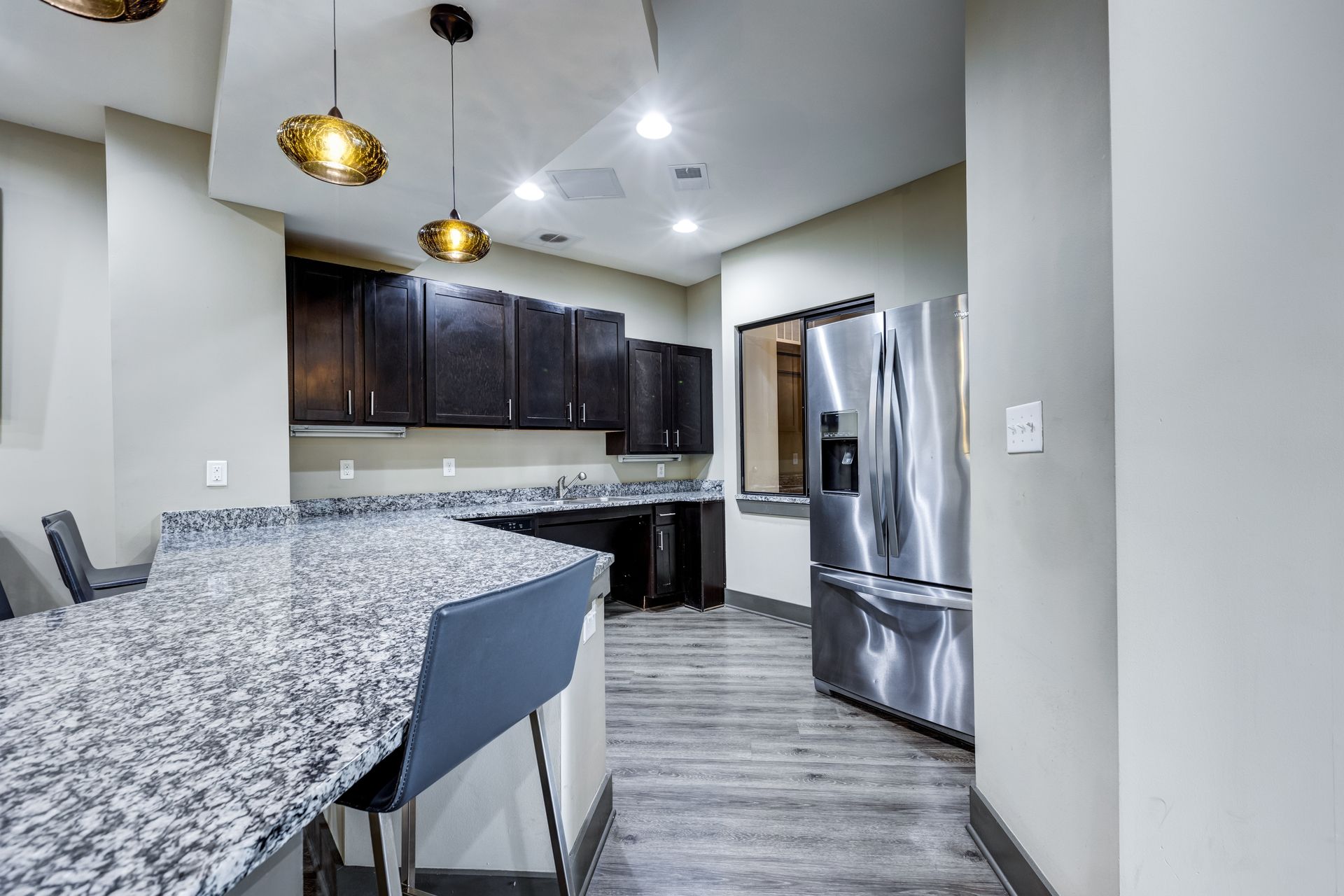 Kitchen with granite countertop, dark cabinets, stainless steel refrigerator, and hanging gold lights at Town Center at Lake Carolina in Columbia, SC.