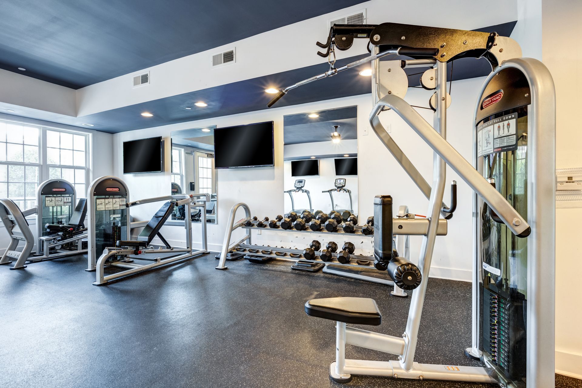 Gym with weight machines, free weights, and TVs on a blue and white painted ceiling at Town Center at Lake Carolina in Columbia, SC.